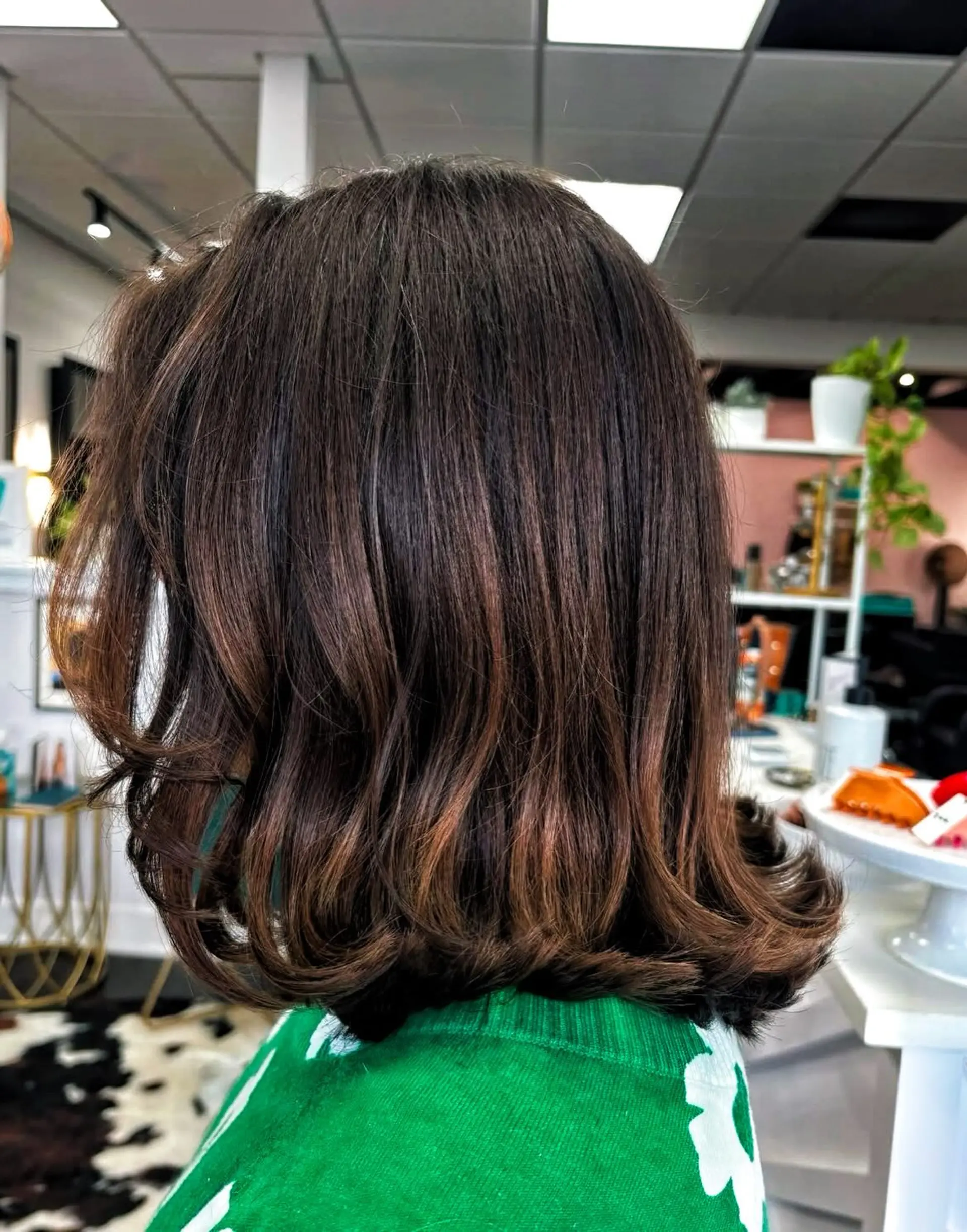 A rich brunette shoulder-length lob styled with smooth body and flipped, bouncy curled ends. 1