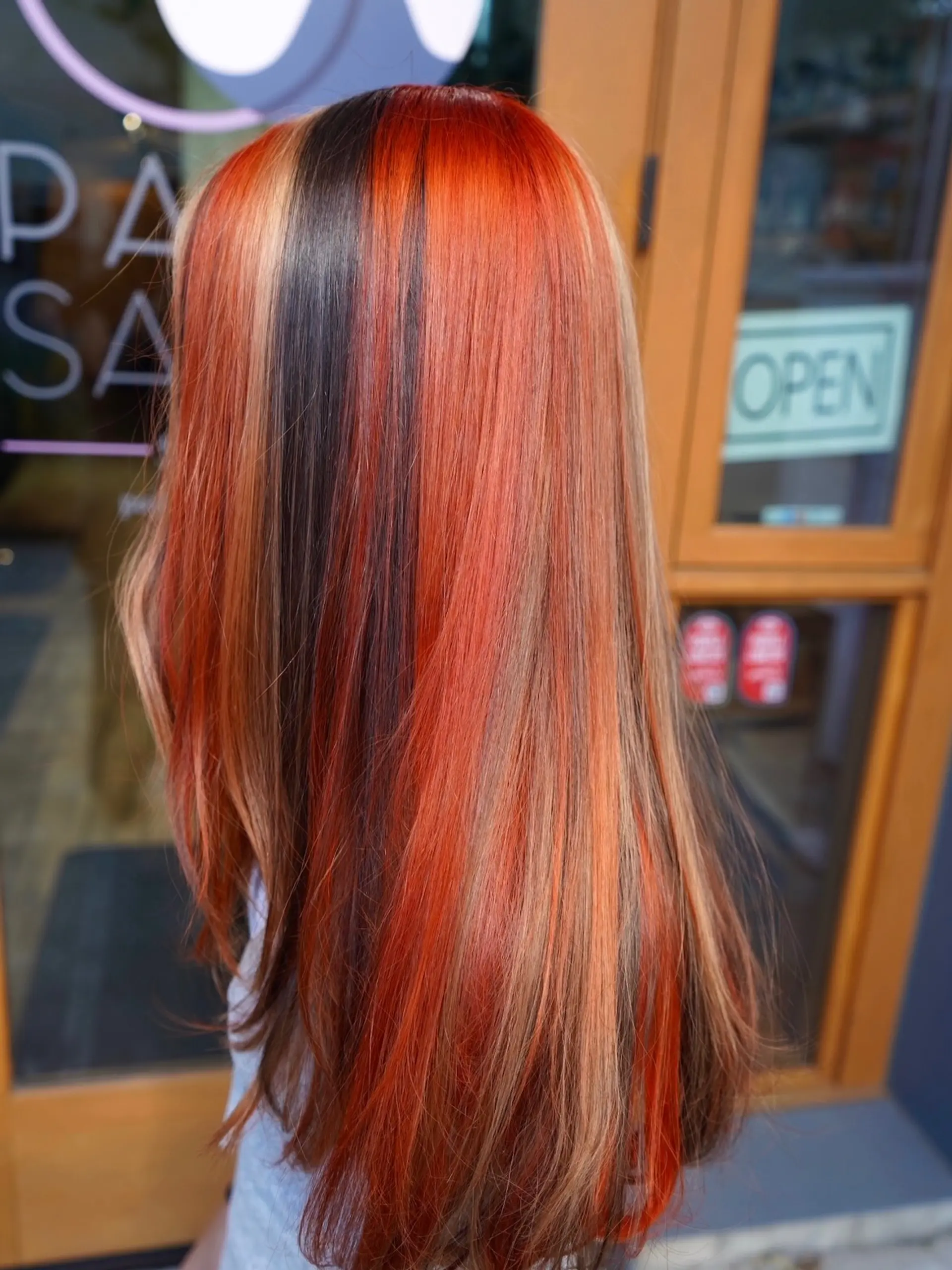 Long straight hair showcasing a bold calico color block pattern with vivid orange, dark brown, and blonde strands. 1