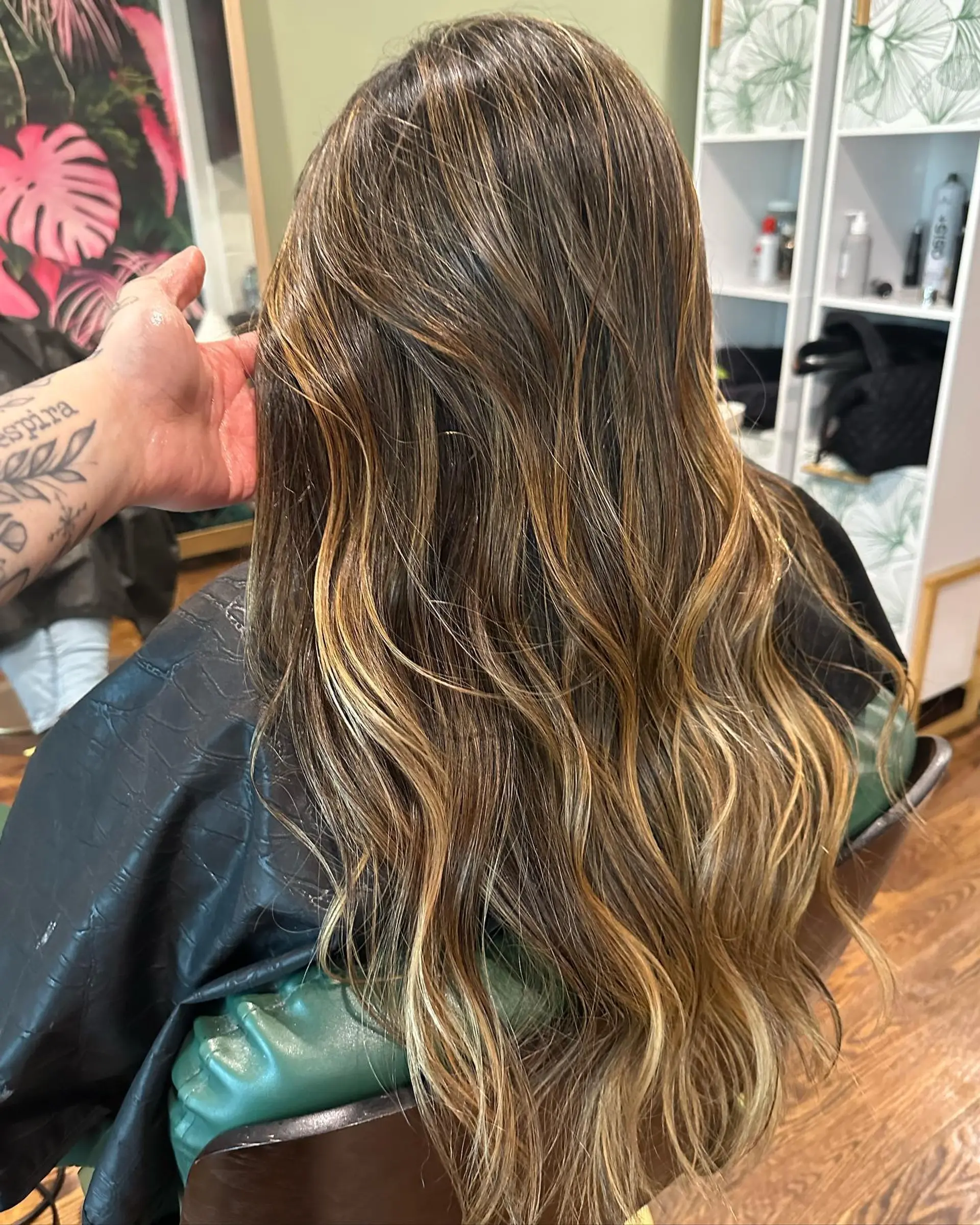 Long dark brown hair featuring warm caramel and honey balayage highlights styled in soft, cascading waves. 1