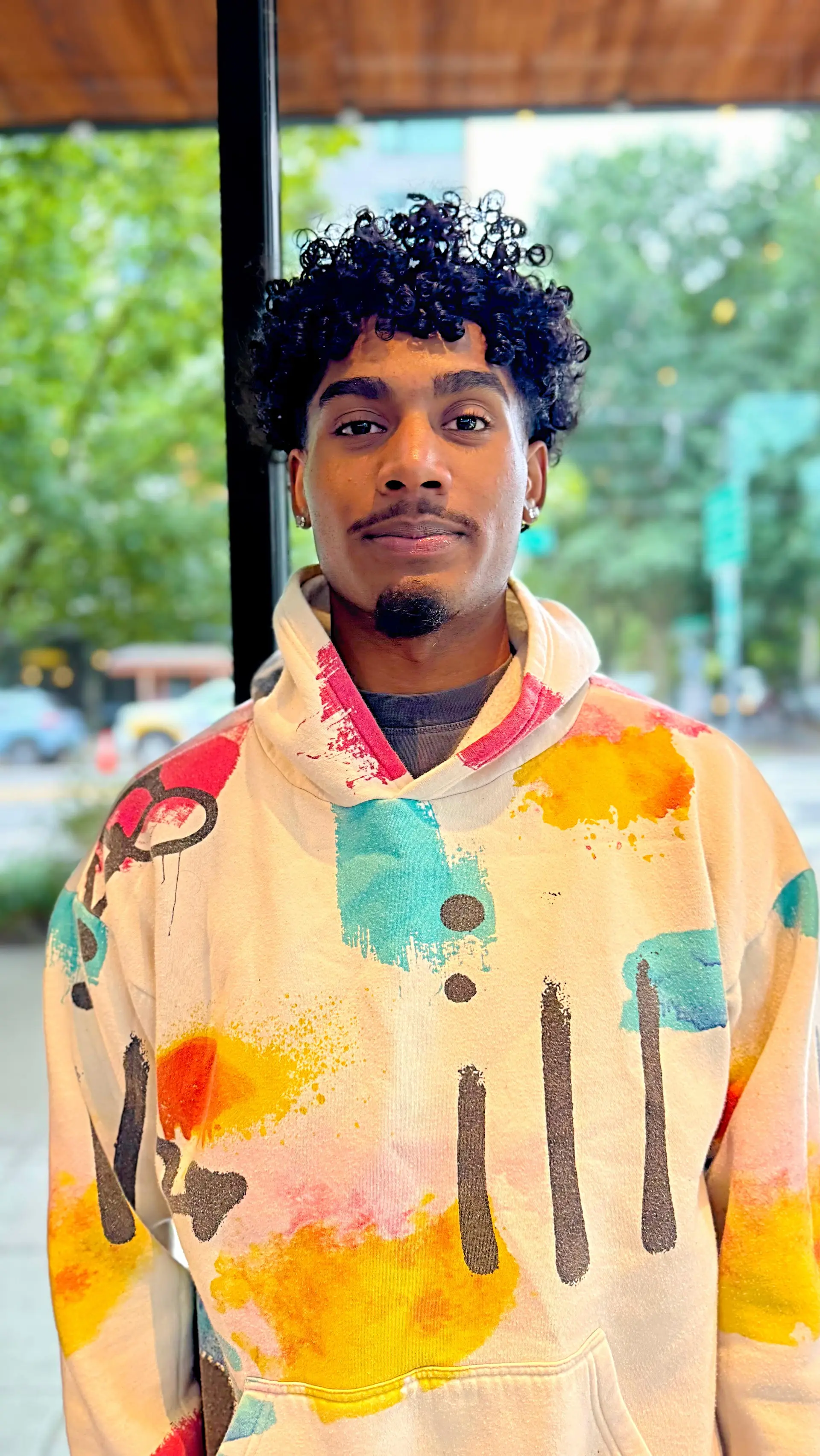 A shaped men's curly haircut featuring glossy, well-defined spiral curls on top with tapered sides. 1