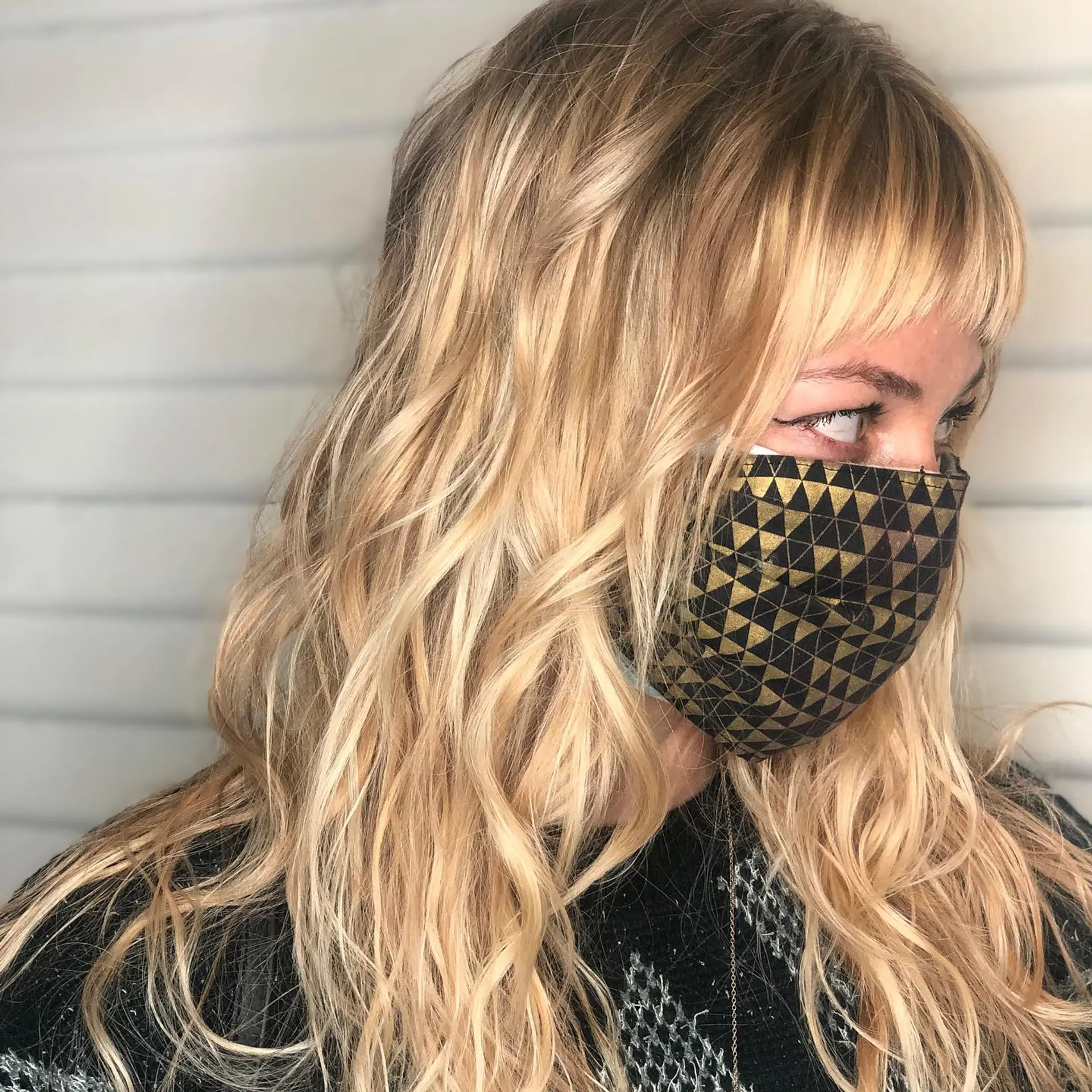 Warm golden blonde balayage styled in loose, textured waves with short straight-across fringe. 1