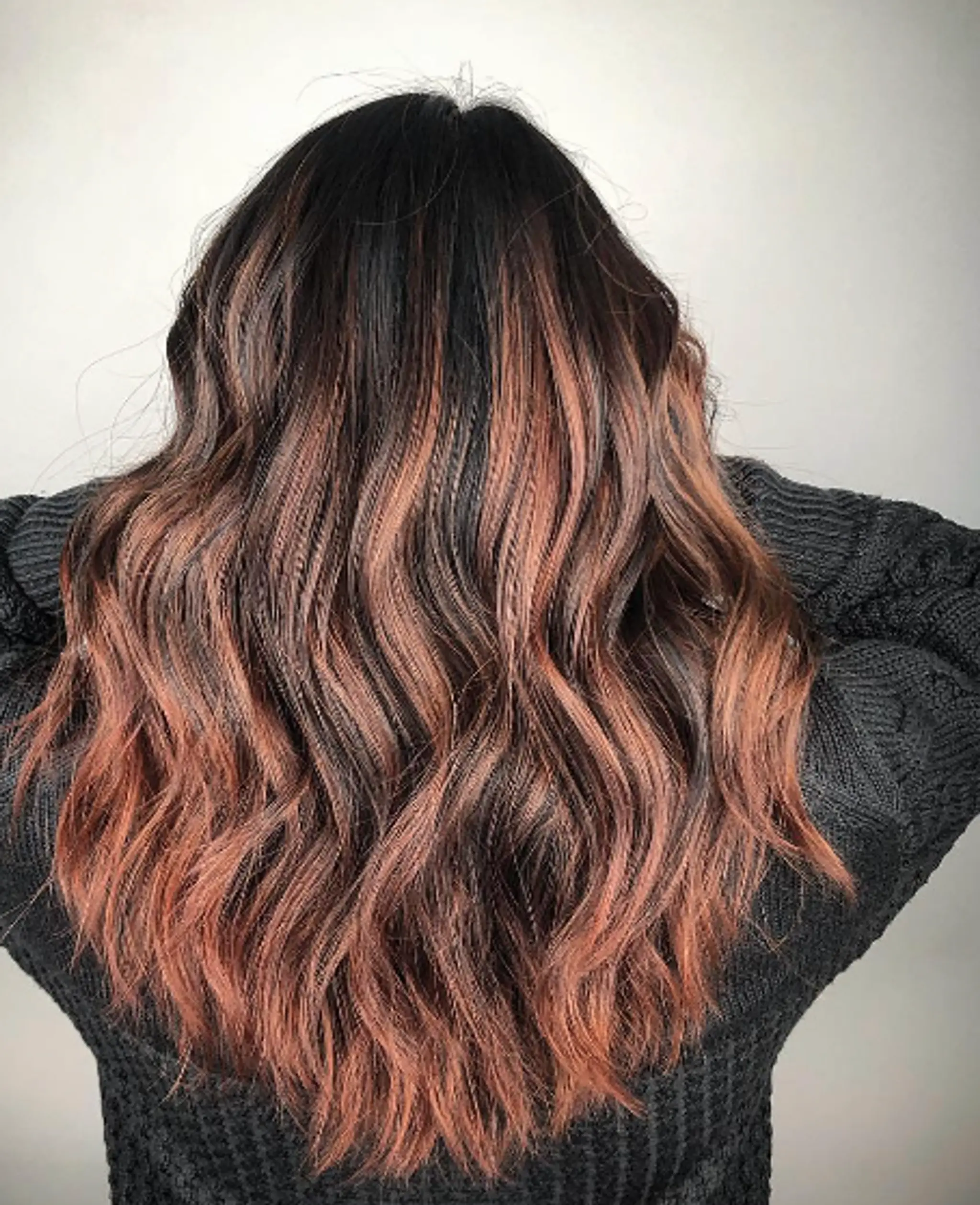 Long, dark brown wavy hair with copper balayage, soft waves, and layered texture.
