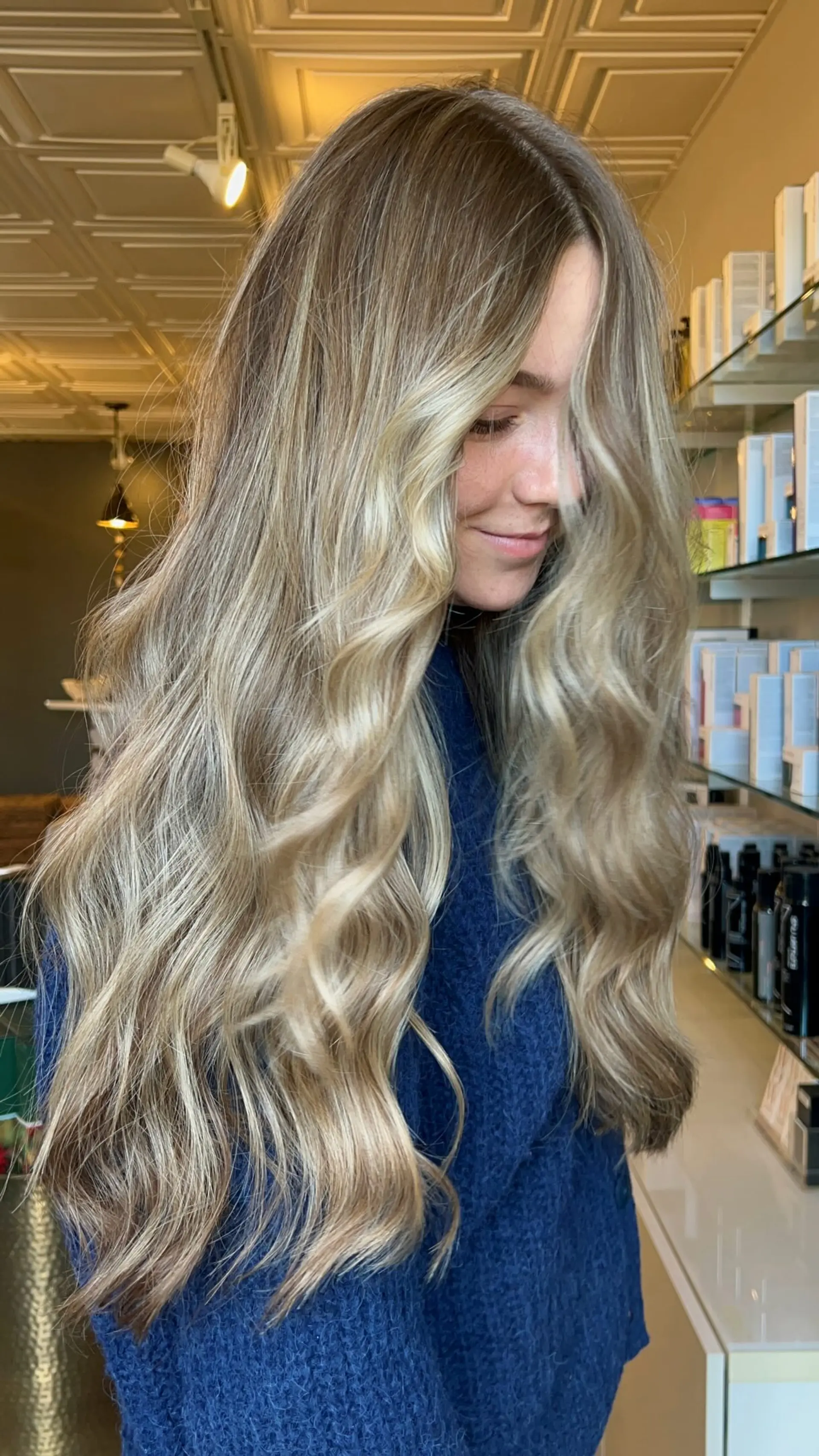 Long hair featuring a multi-tonal dimensional blonde balayage styled with soft, voluminous waves. 1