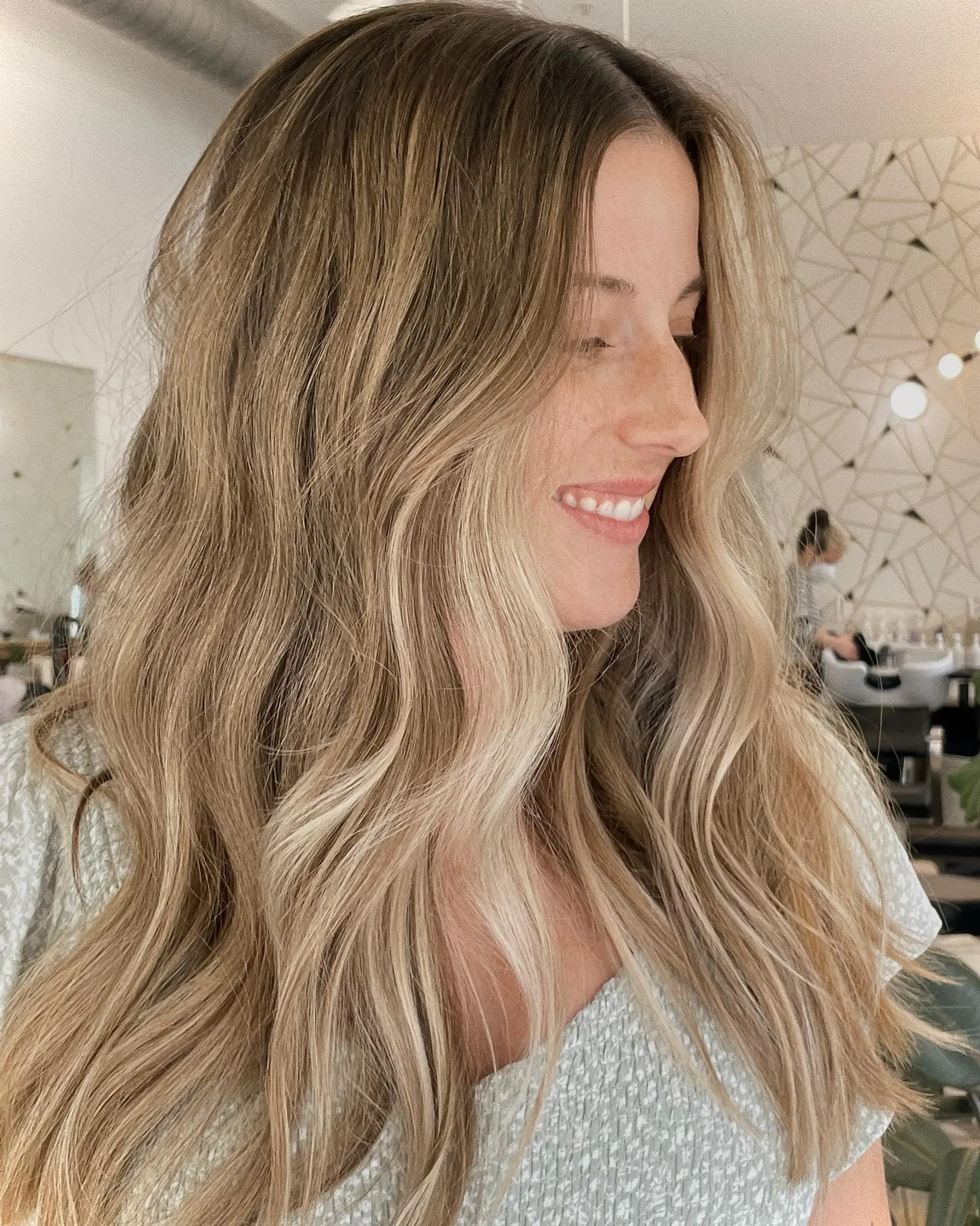 Long sun-kissed blonde hair styled with loose, beachy waves and soft face-framing layers. 1