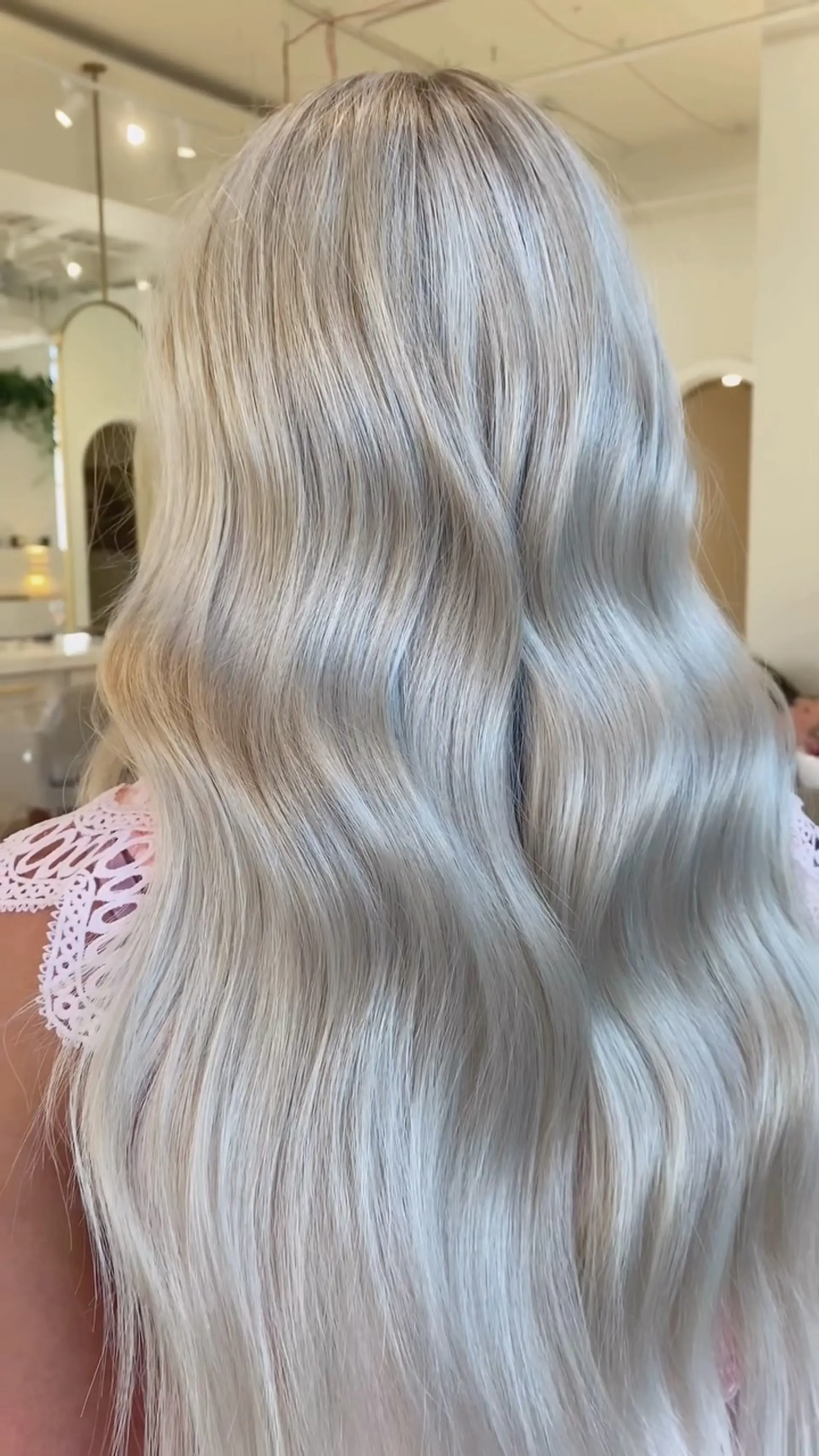 Long, flowing platinum blonde hair styled into soft, elegant waves with a smooth and seamless finish. 1