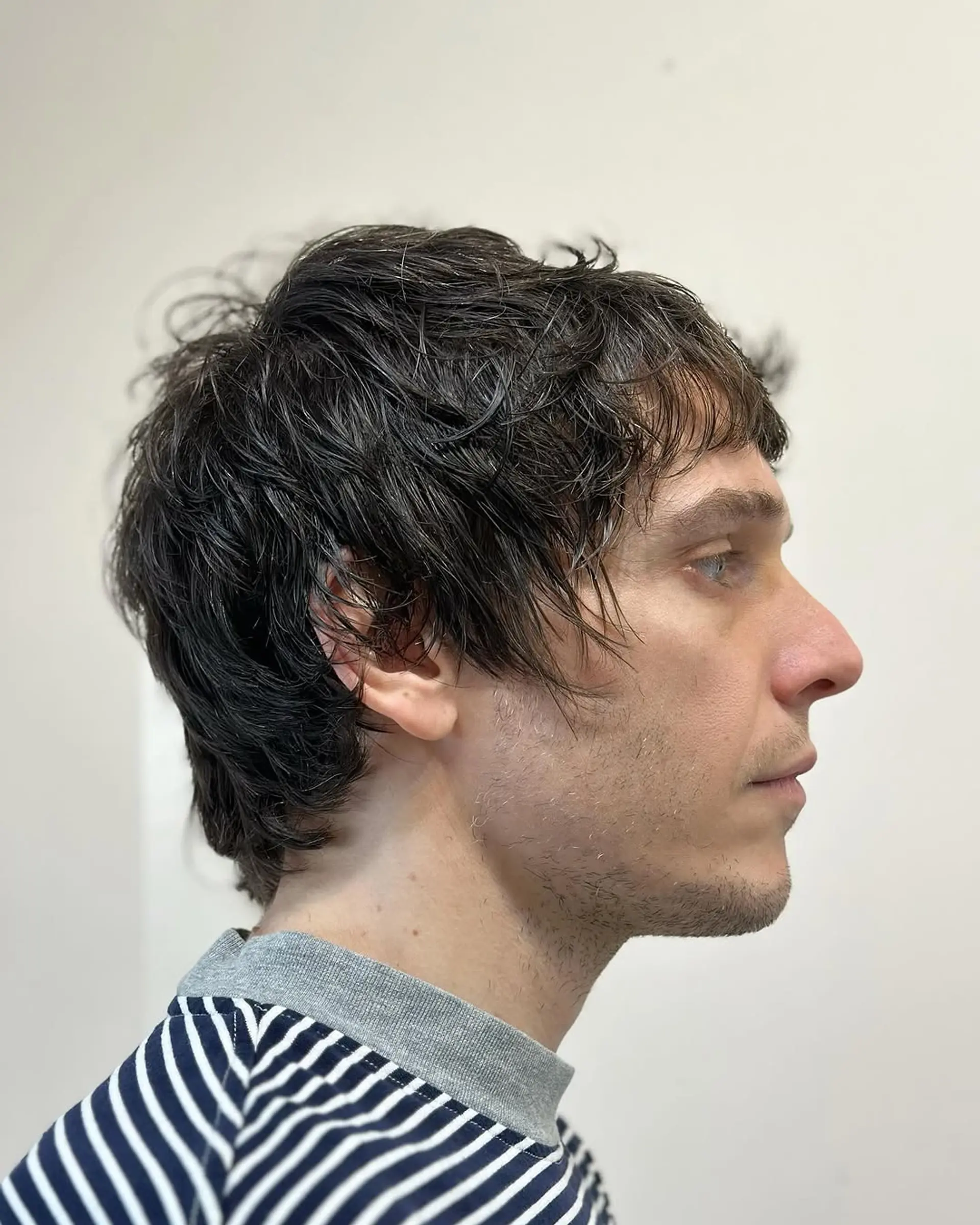 A medium-length, wavy, dark brown hairstyle with textured layers and a side-swept fringe, presenting a casual, tousled appearance. 1