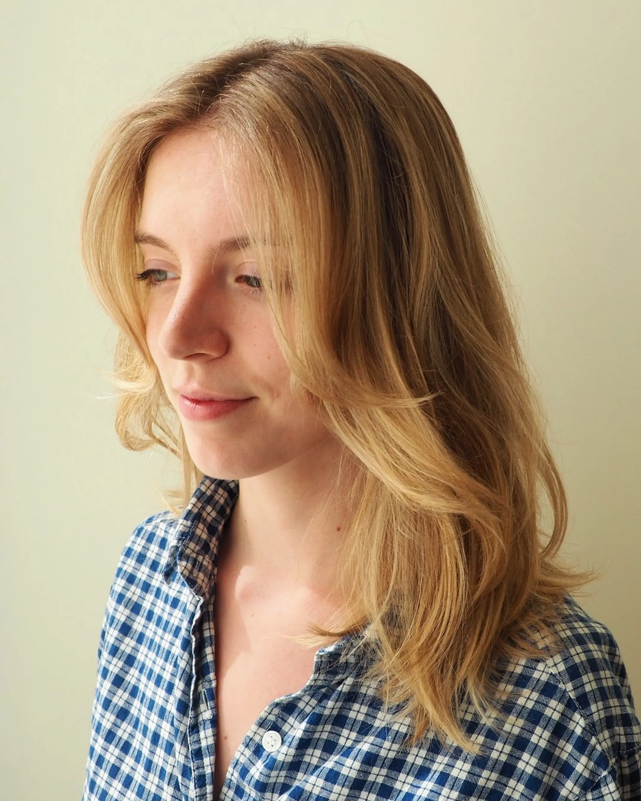 Soft, medium-length wavy hairstyle with natural blonde tones and a subtle side part, exuding a sun-kissed elegance.