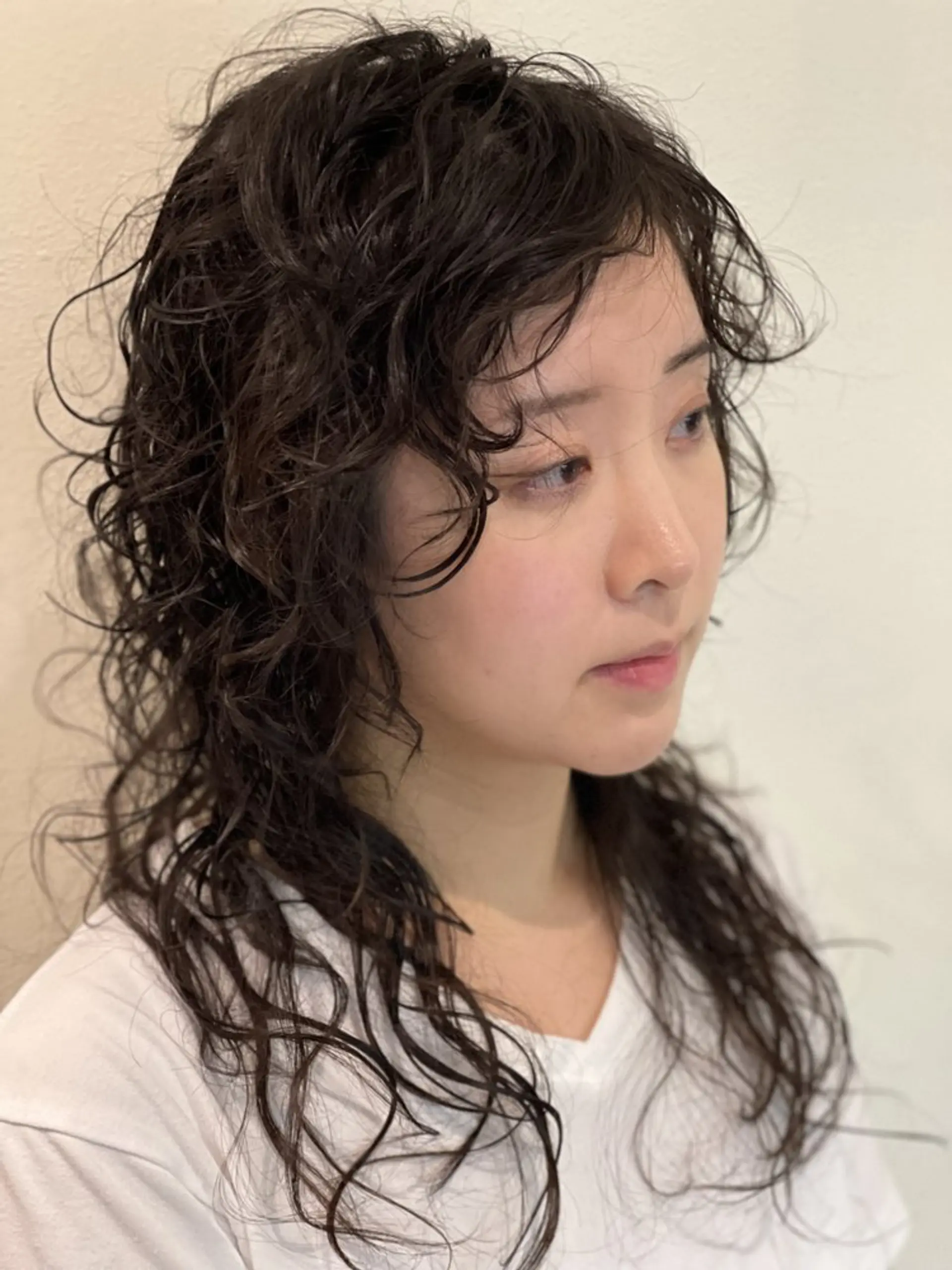 A trendy, layered shag haircut with curly bangs that blends the edginess of a mullet with modern styling. 1