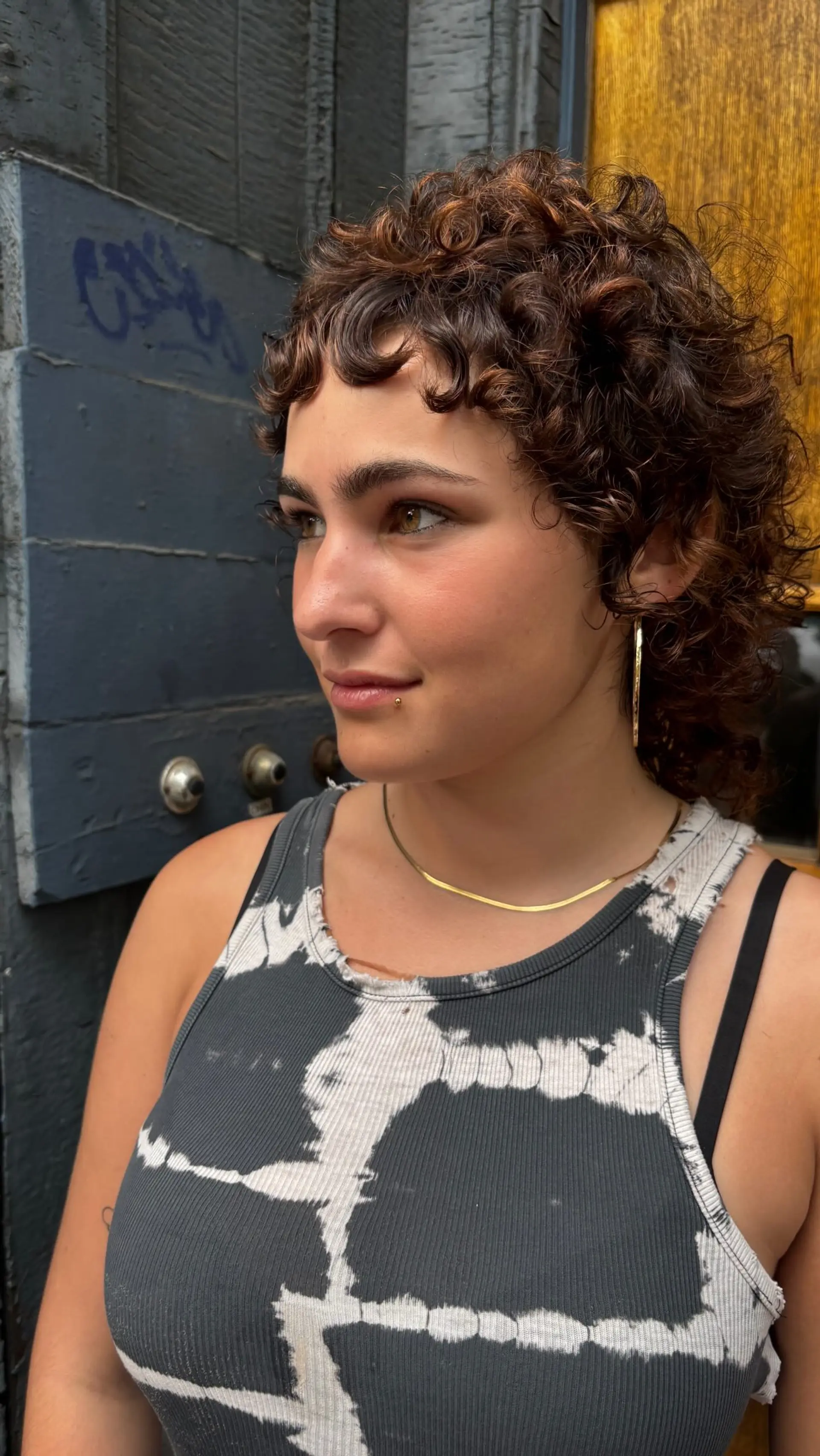 A textured curly mullet featuring cropped micro bangs and voluminous curls throughout the top, sides, and back. 1