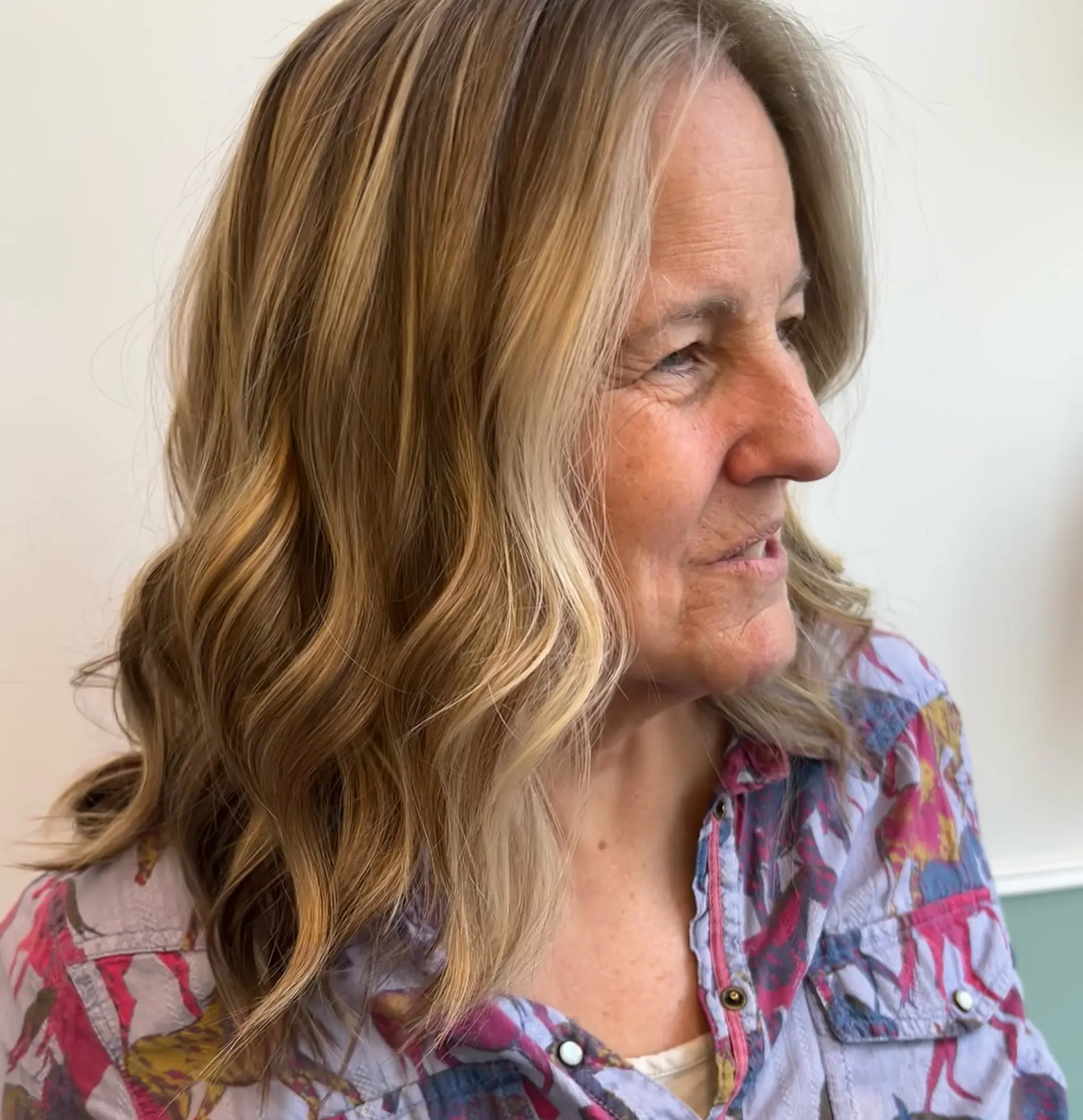 Collarbone-length hair styled in soft, loose waves with multi-tonal honey blonde highlights. 1