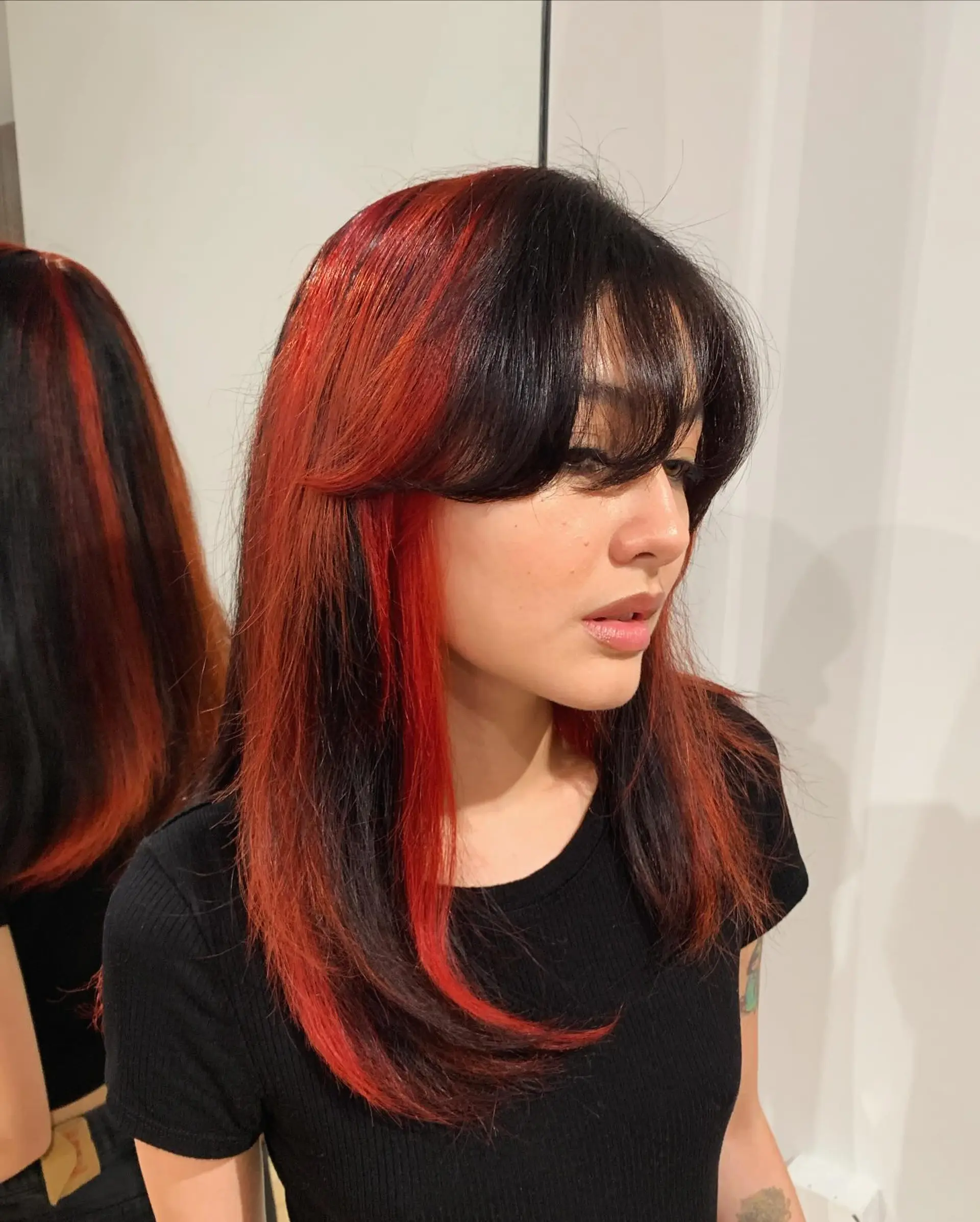 A long, straight hairstyle featuring bold black and red hues. It is accented with soft layers and fringe bangs, offering a striking and elegant contrast. 1