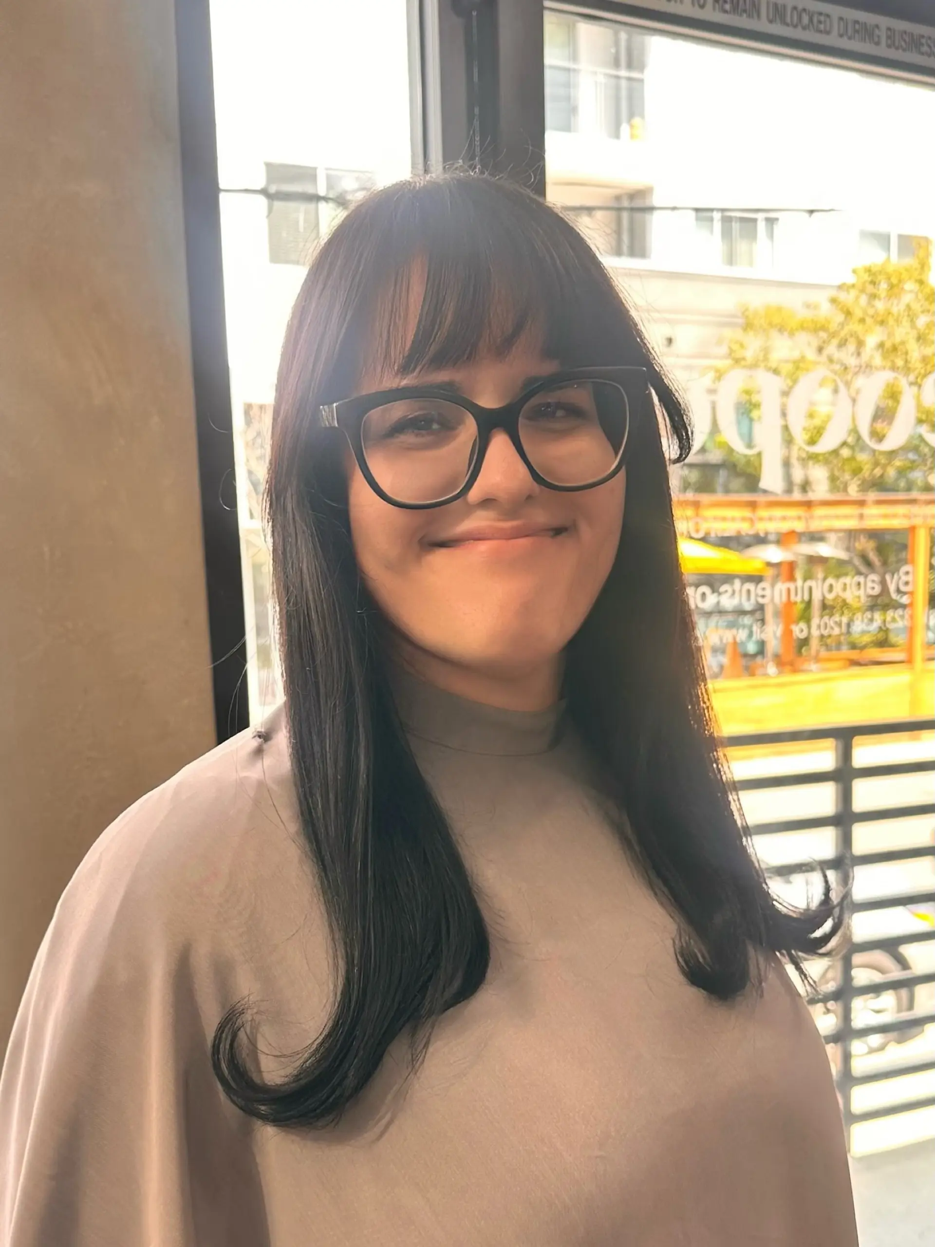 Medium-length dark brunette hair styled with full front bangs and playful flipped ends. 1