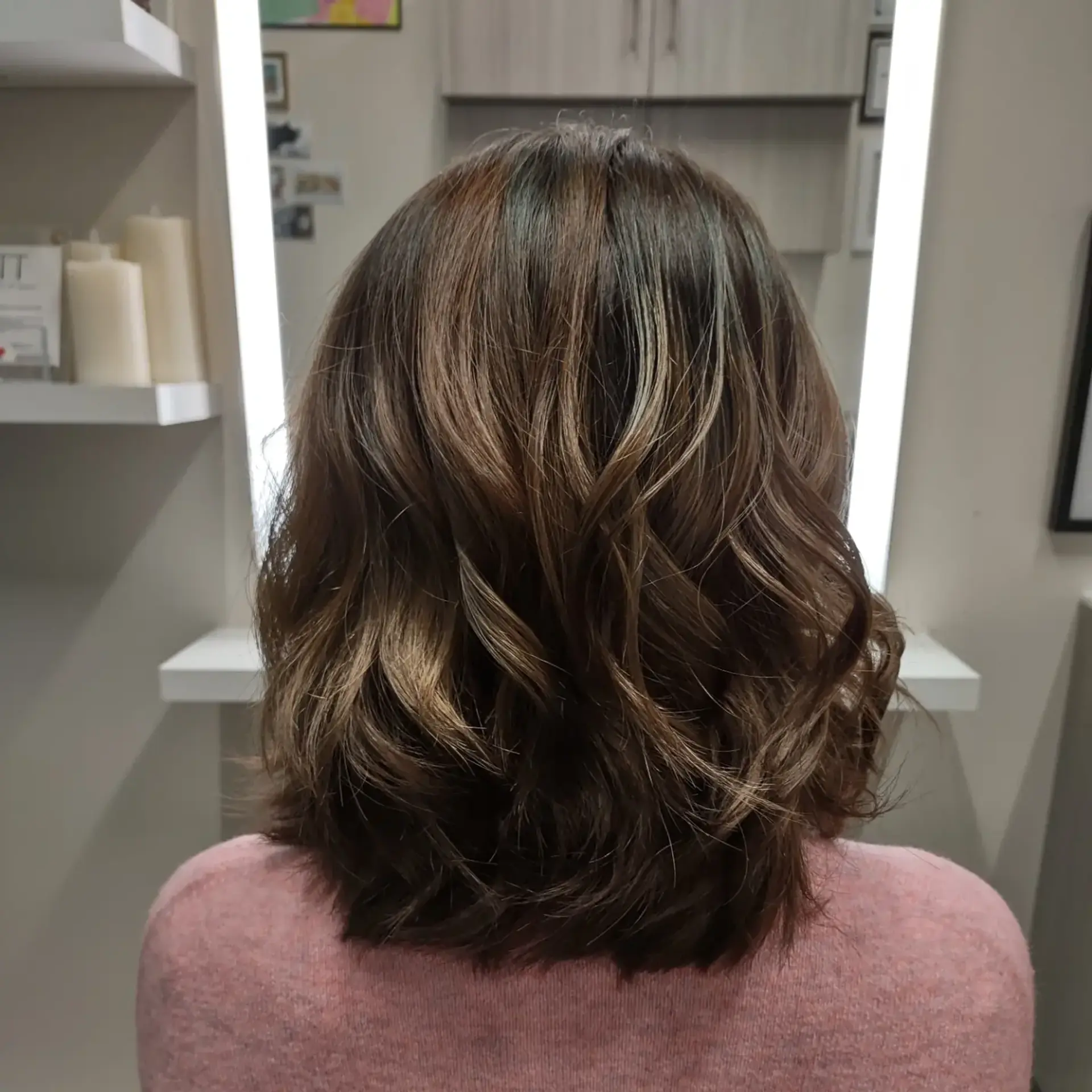 A textured shoulder-length lob styled with loose, dimensional waves in warm brunette tones. 1