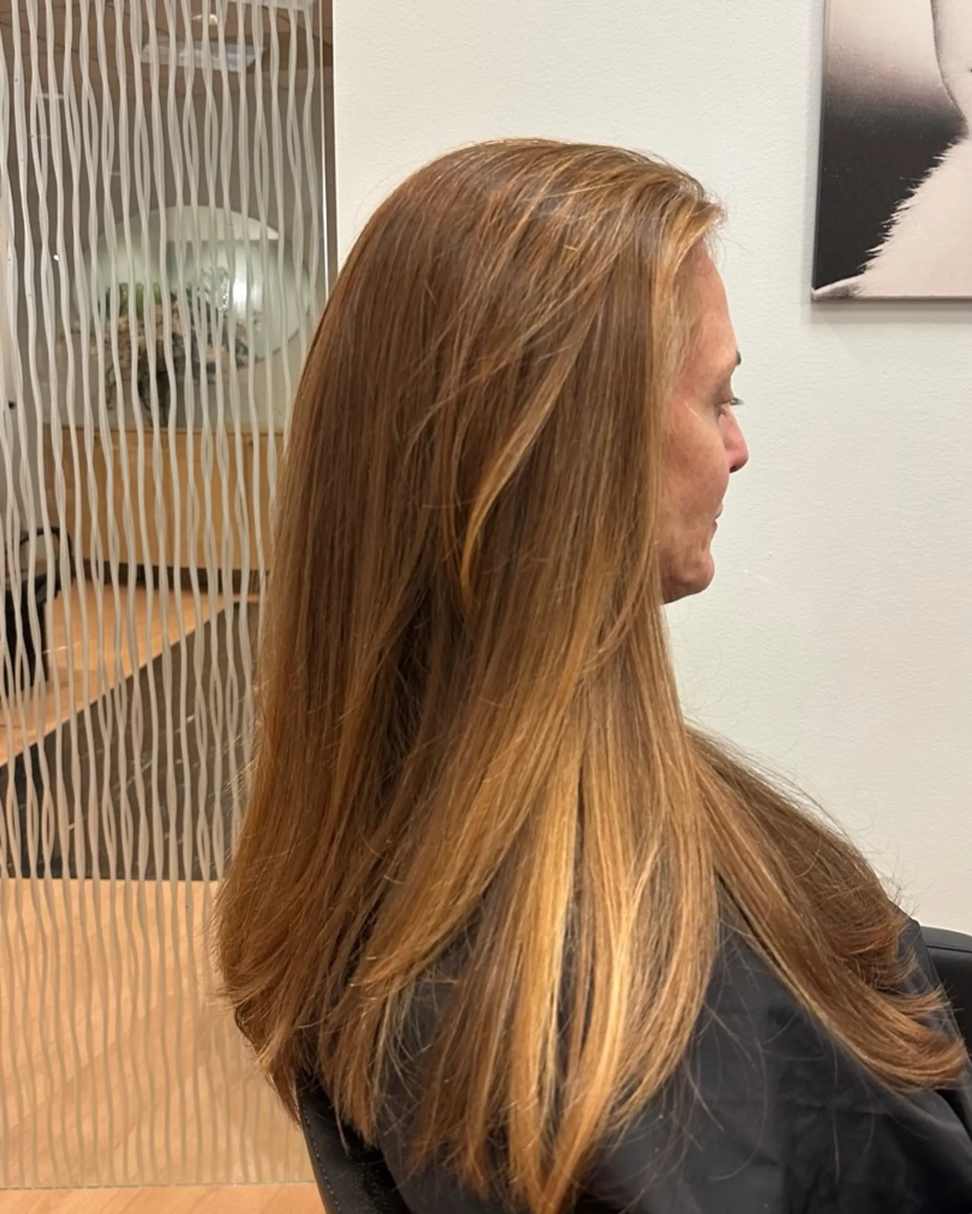 Long layered warm strawberry blonde hair smoothly blown out with soft face framing. 1