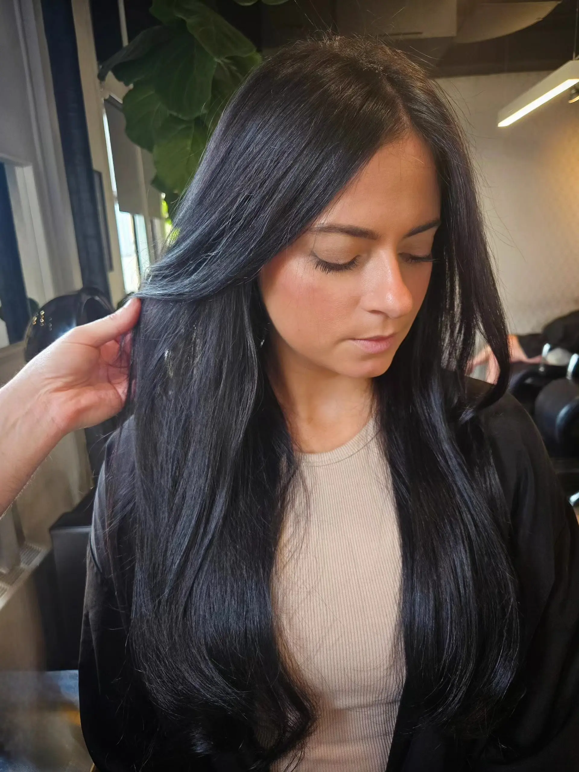 Long, glossy jet-black hair with face-framing layers styled into a smooth, sleek blowout with softly beveled ends. 1