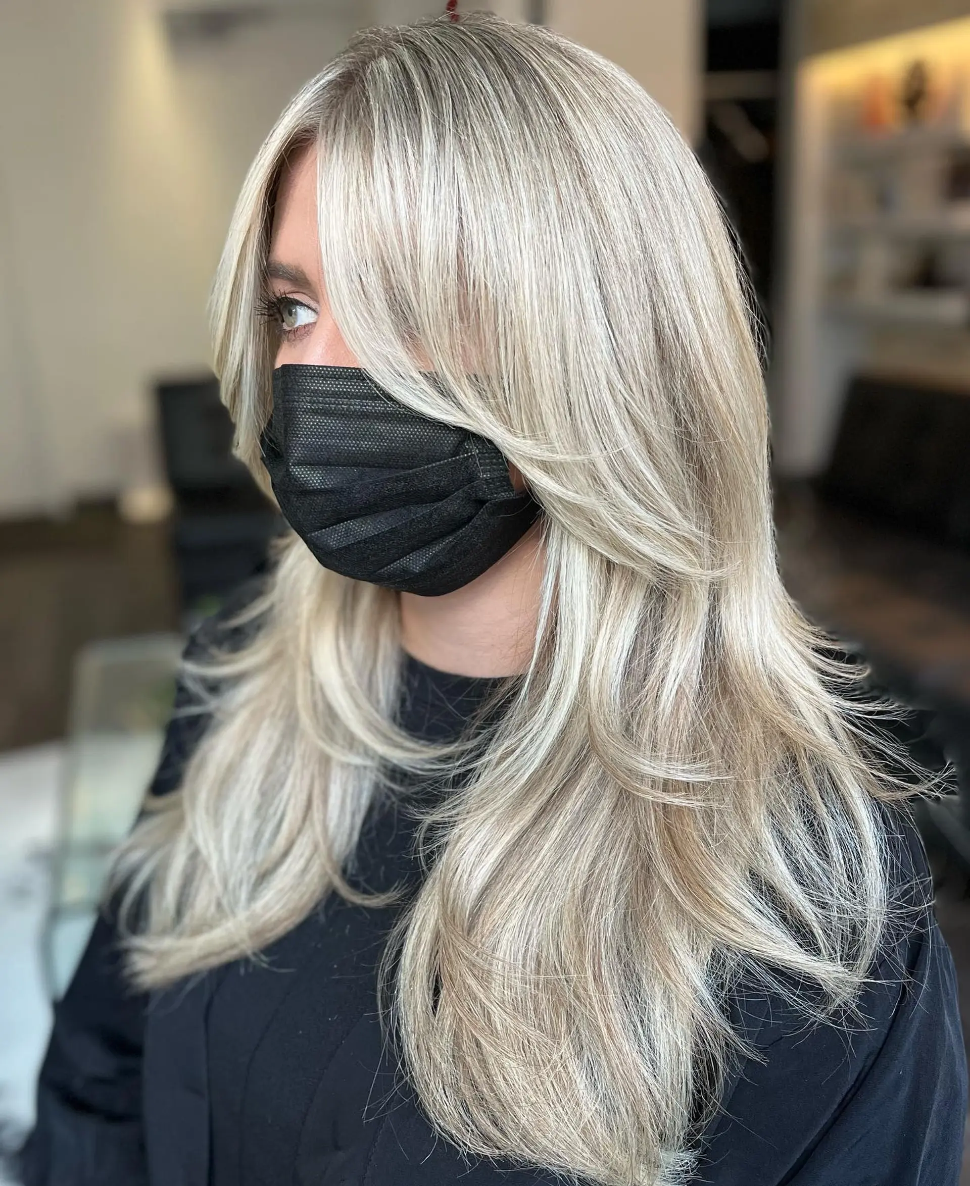 Bright platinum blonde long hair cut with textured face-framing layers and soft curtain bangs. 1