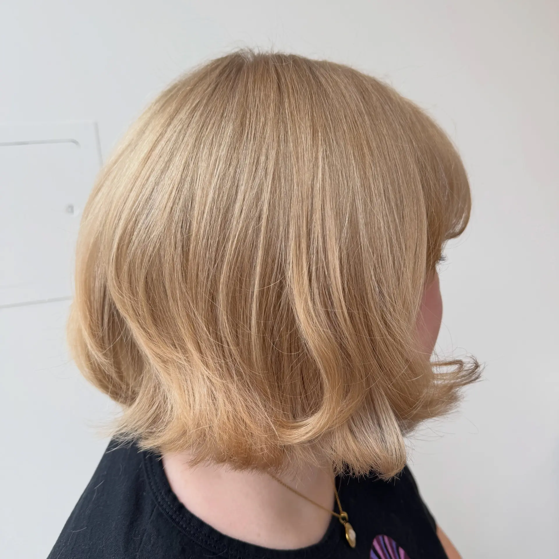 A warm blonde chin-length bob styled with smooth texture and flirty, flipped-out ends. 1
