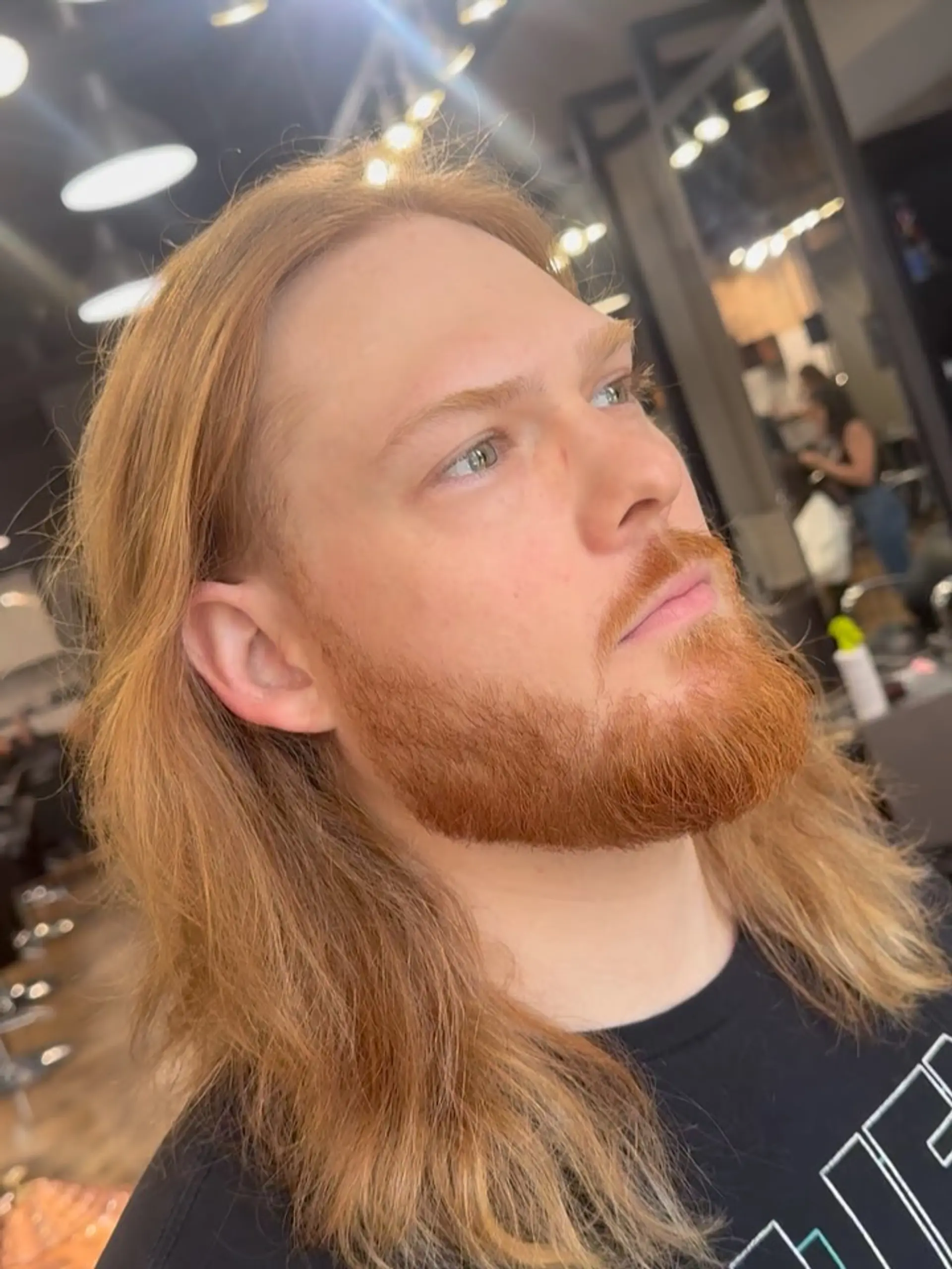 Shoulder-length strawberry blonde hair brushed naturally back and tucked behind the ear, paired with a sculpted full copper beard. 1