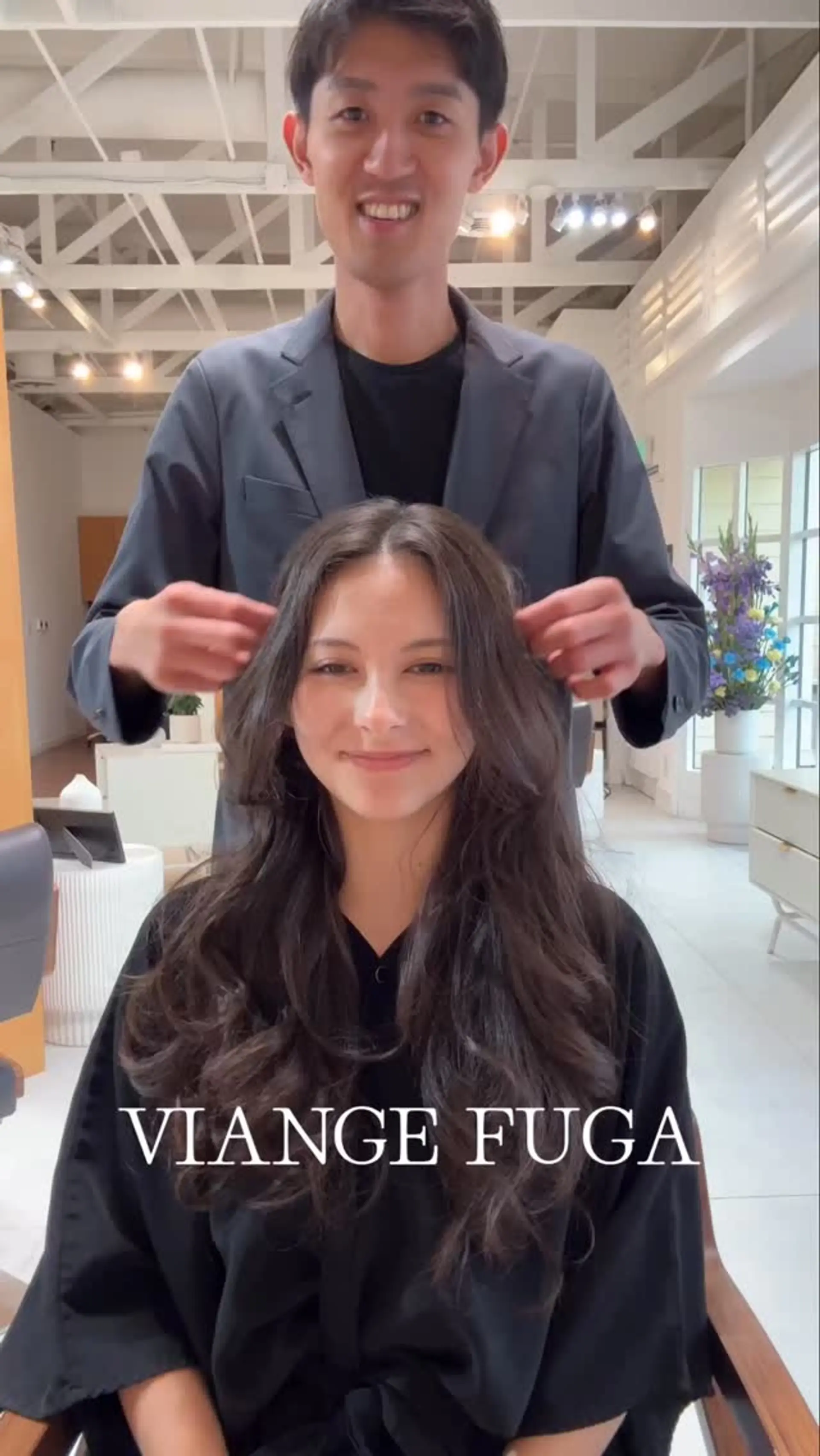 Long dark brown hair cut with face-framing layers and styled into soft, bouncy waves. 1