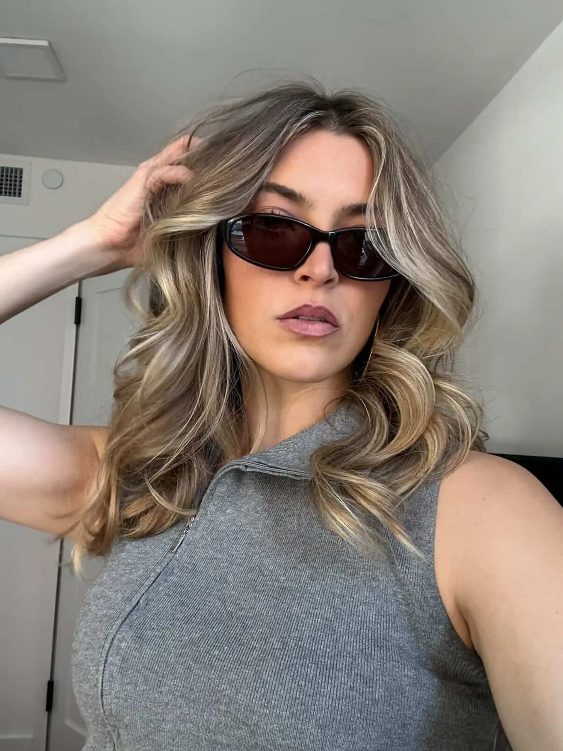 Medium-length ash blonde highlighted hair styled into voluminous blowout waves with curtain layers framing the face. 1