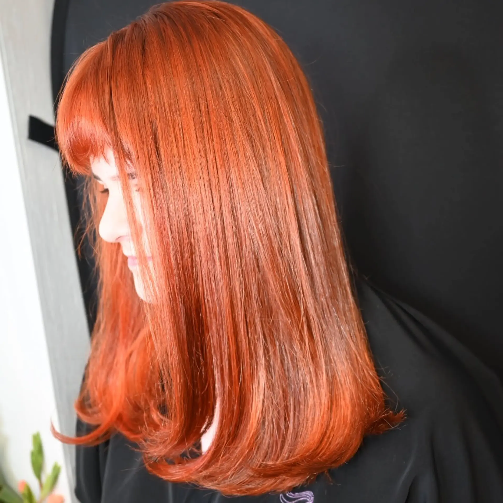 Straight vibrant copper-toned medium-length hair styled with full front bangs and soft, inward-curled ends. 1