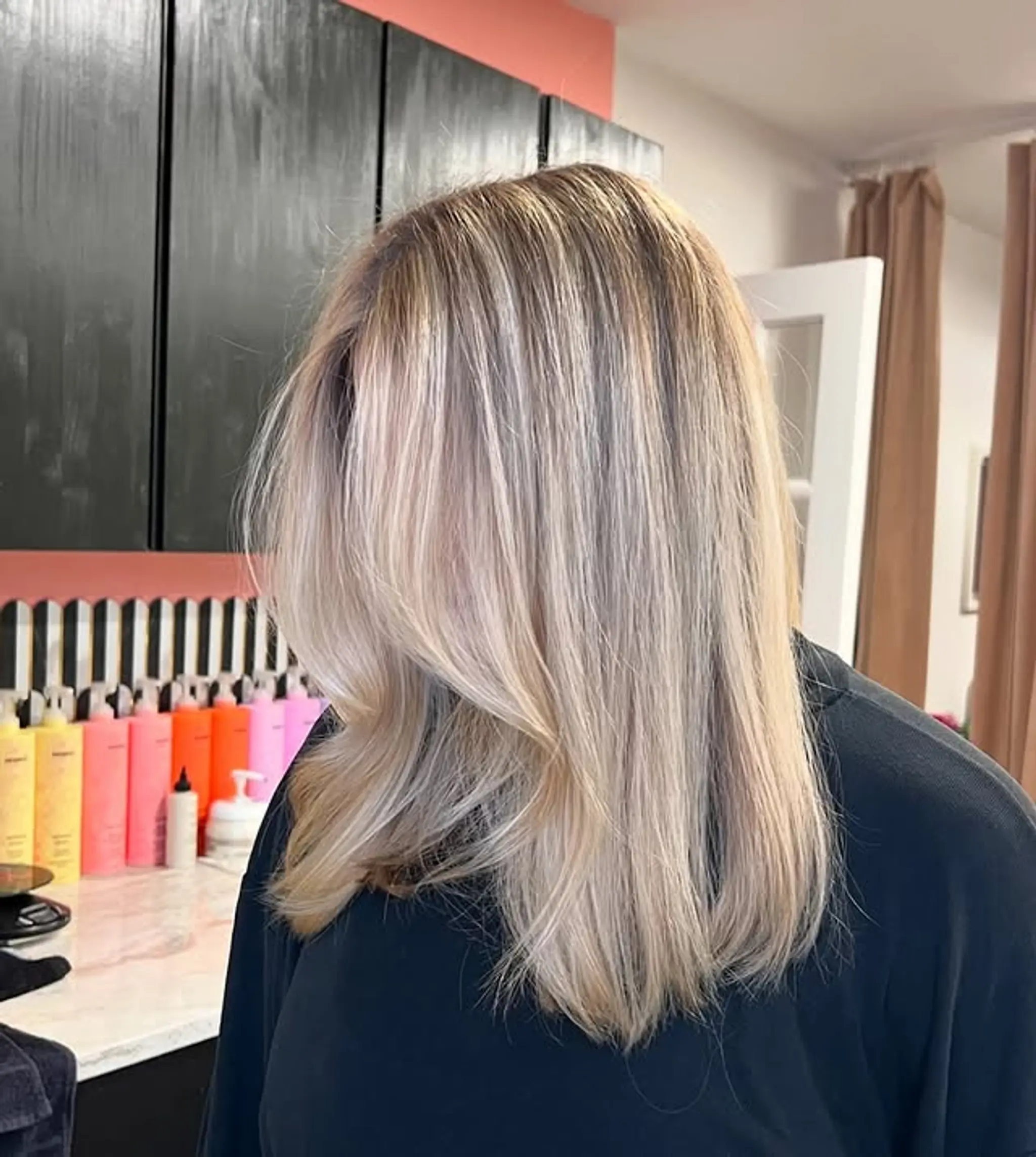 A straight, medium-length hairstyle featuring an icy blonde balayage with face-framing layers for added movement.