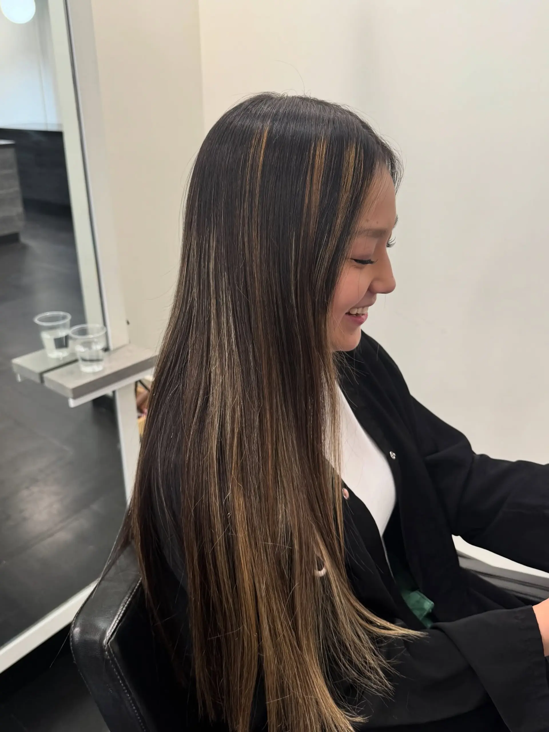 Long, sleek straight dark brown hair enhanced with seamless caramel and honey blonde dimensional balayage highlights. 1