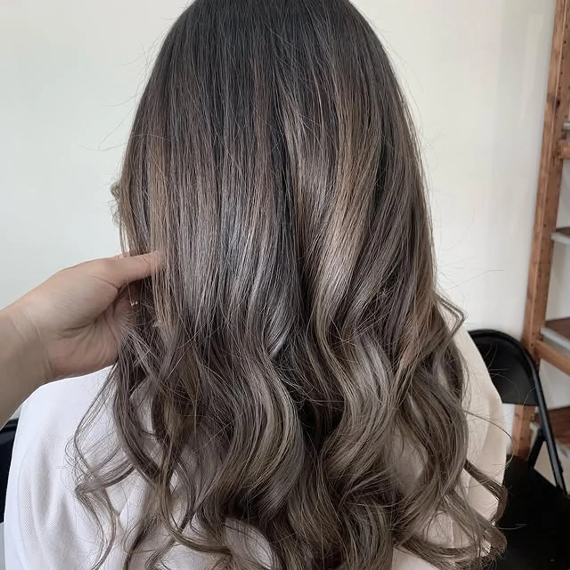 Long, wavy hair with a balayage that transitions from dark brown roots to ashy brown and grey ends. 1
