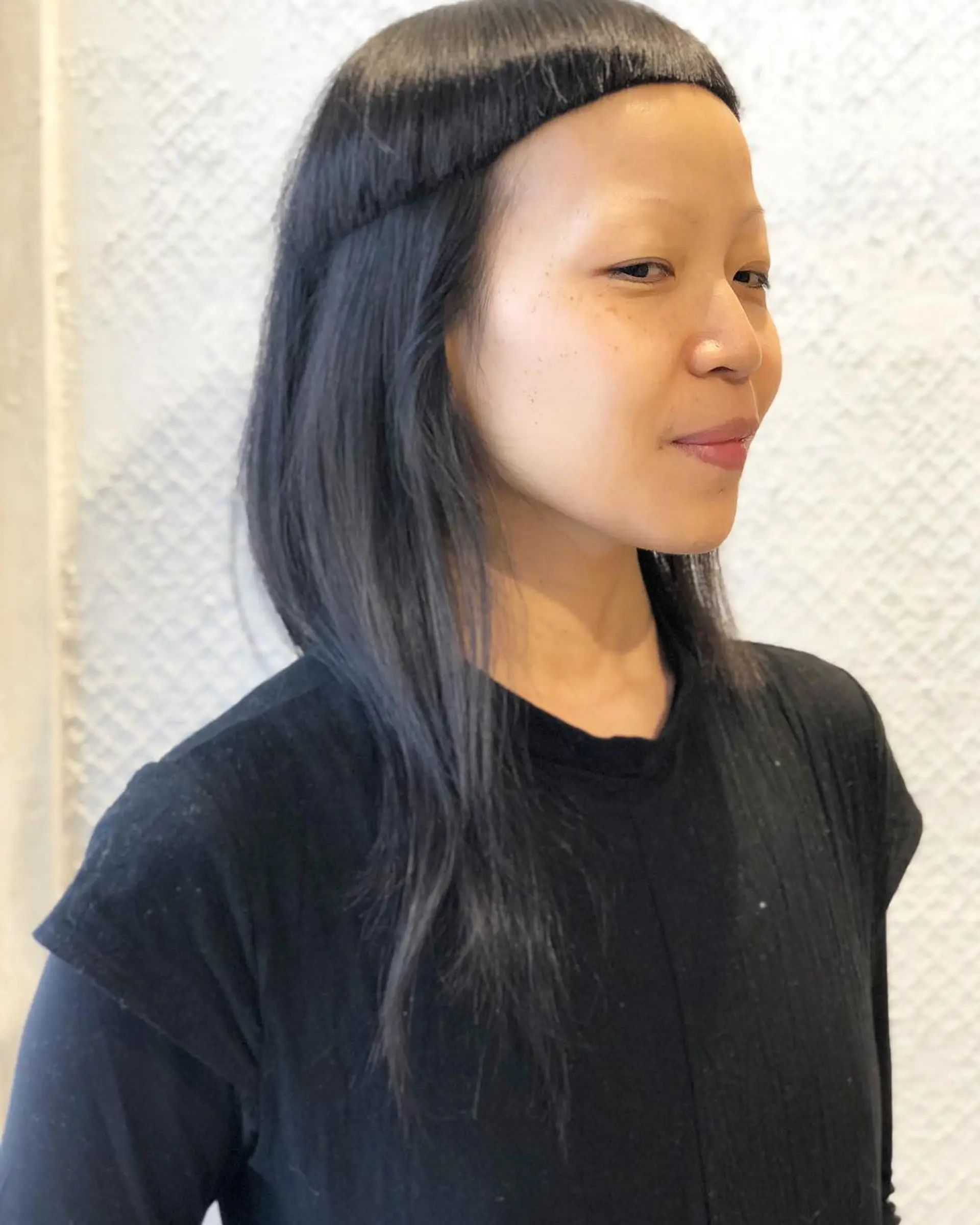 An edgy hairstyle with a blunt arc fringe combined with medium-length sleek black hair, emphasizing a minimalist and avant-garde look. 1