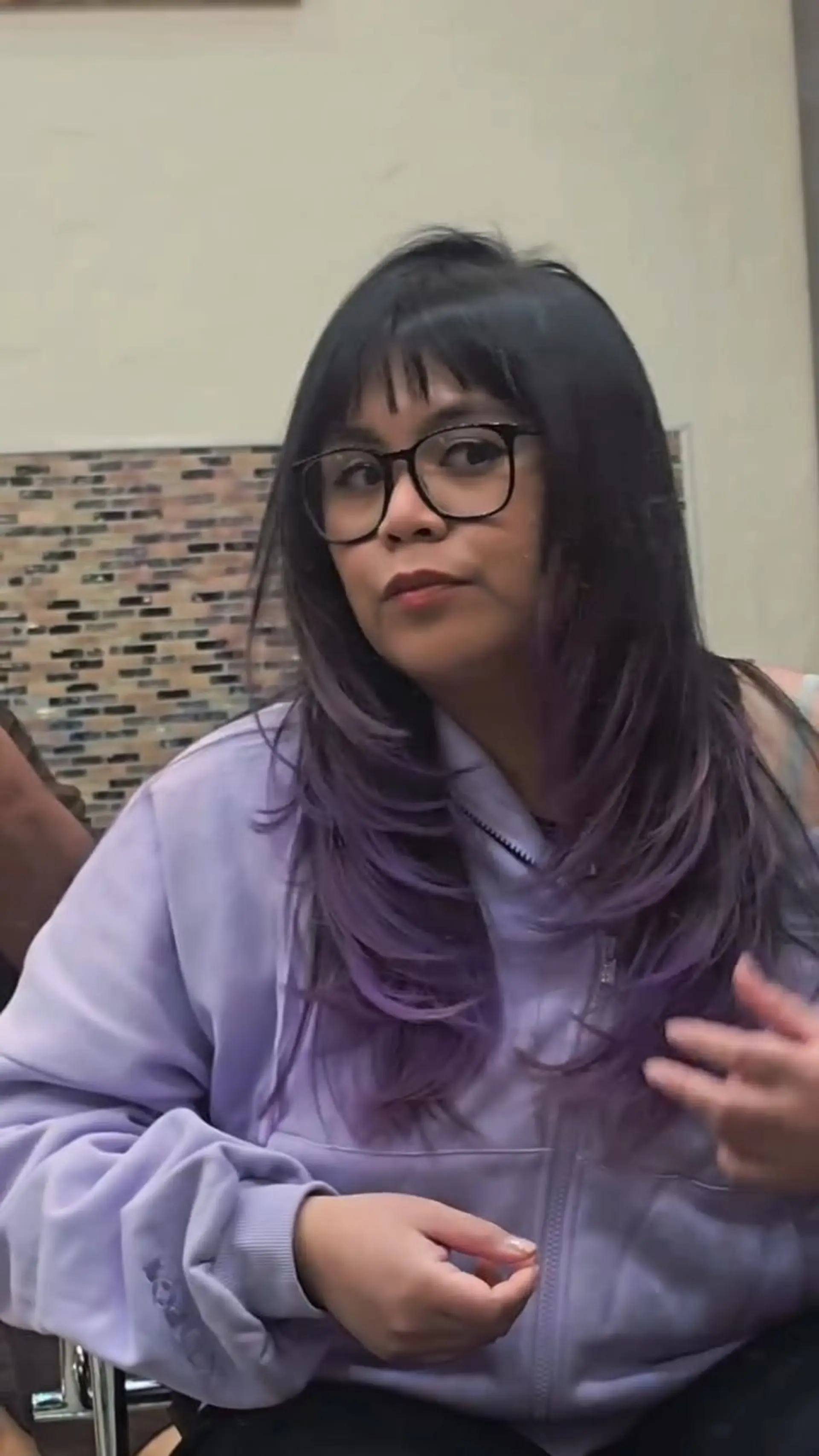Long feathered layers featuring a seamless blend from dark roots into soft lavender-purple ends, paired with straight-across textured bangs. 1