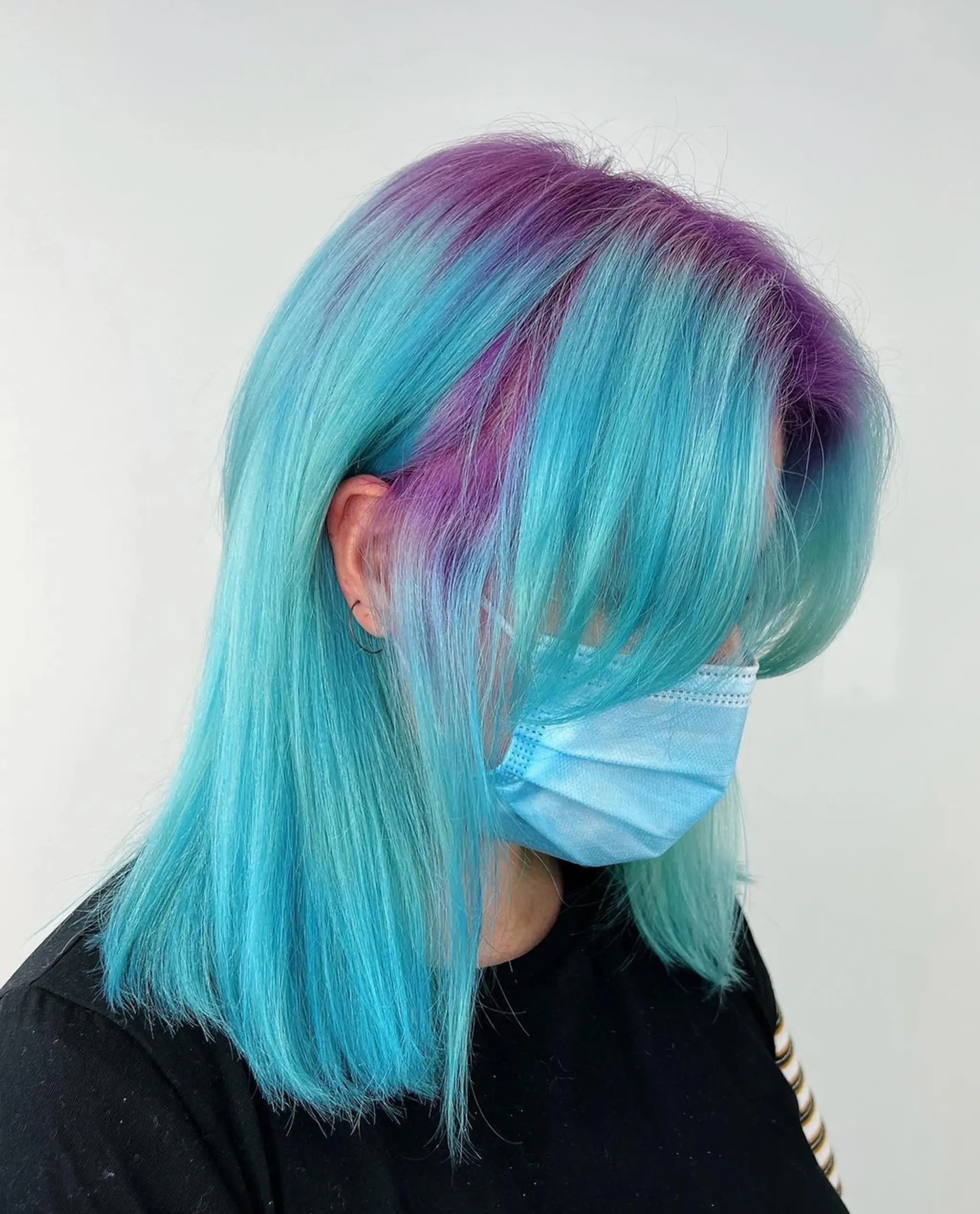 Medium-length, straight hair with a two-tone pastel effect of sky blue and lavender colors, featuring layered bangs.