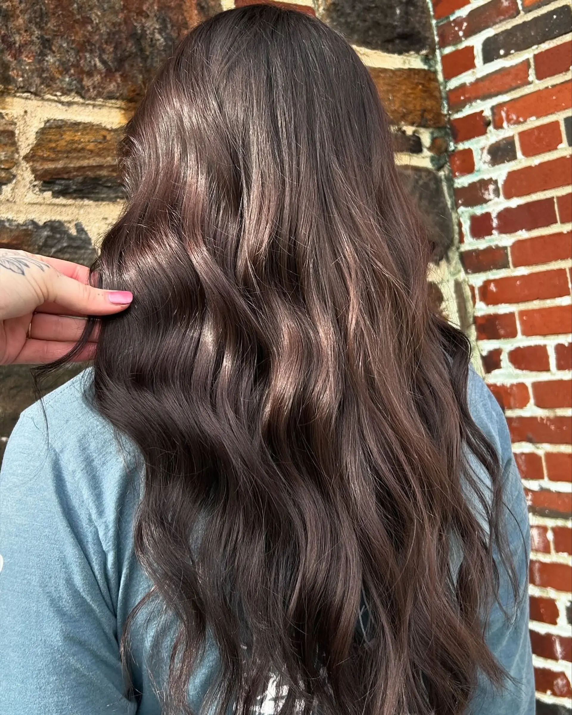 Long, rich brunette hair featuring high shine and styled into soft, cascading waves. 1