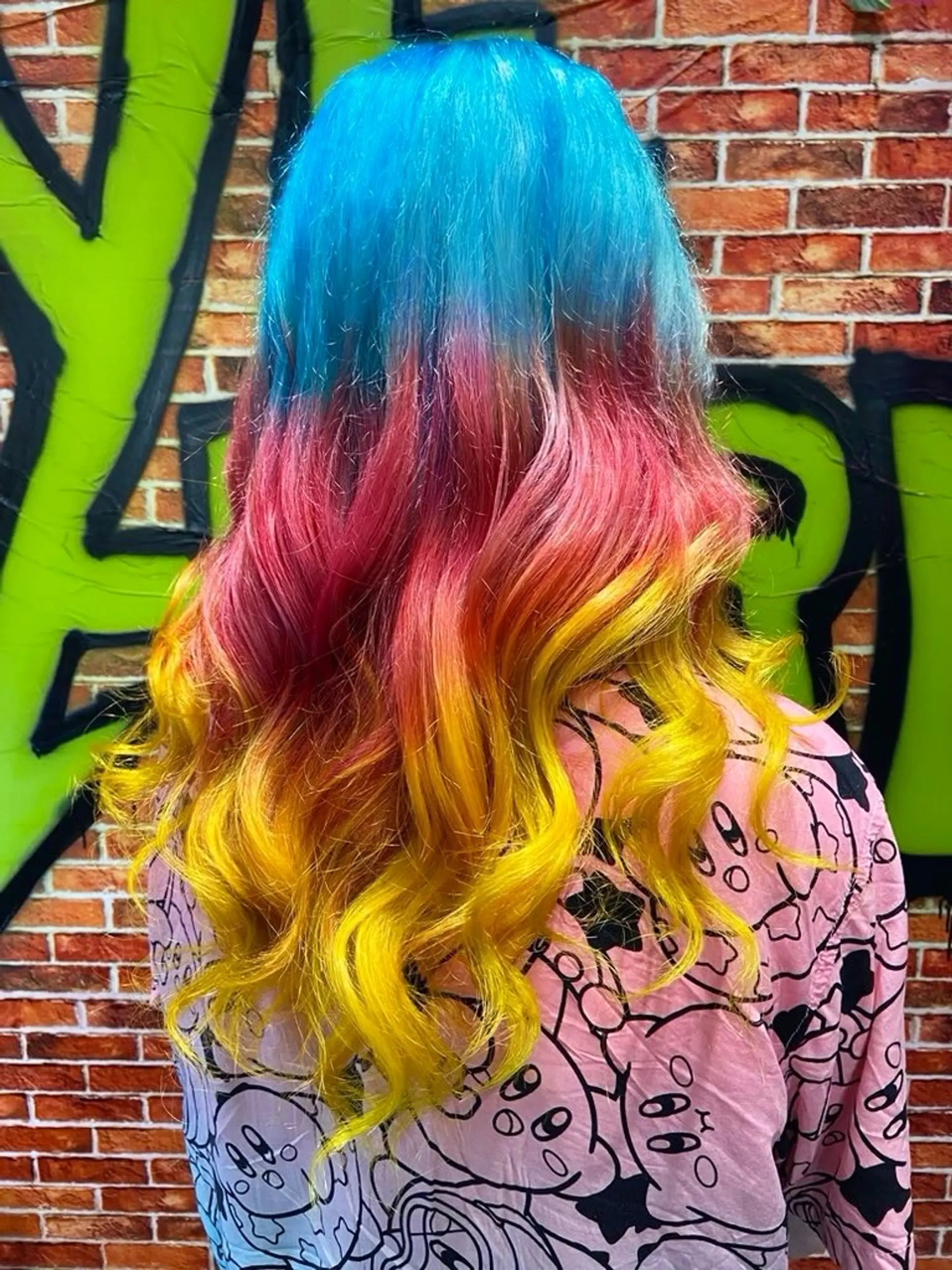 Long wavy hair styled with a vibrant three-tone color melt shifting from bright blue to magenta pink and vivid yellow. 1