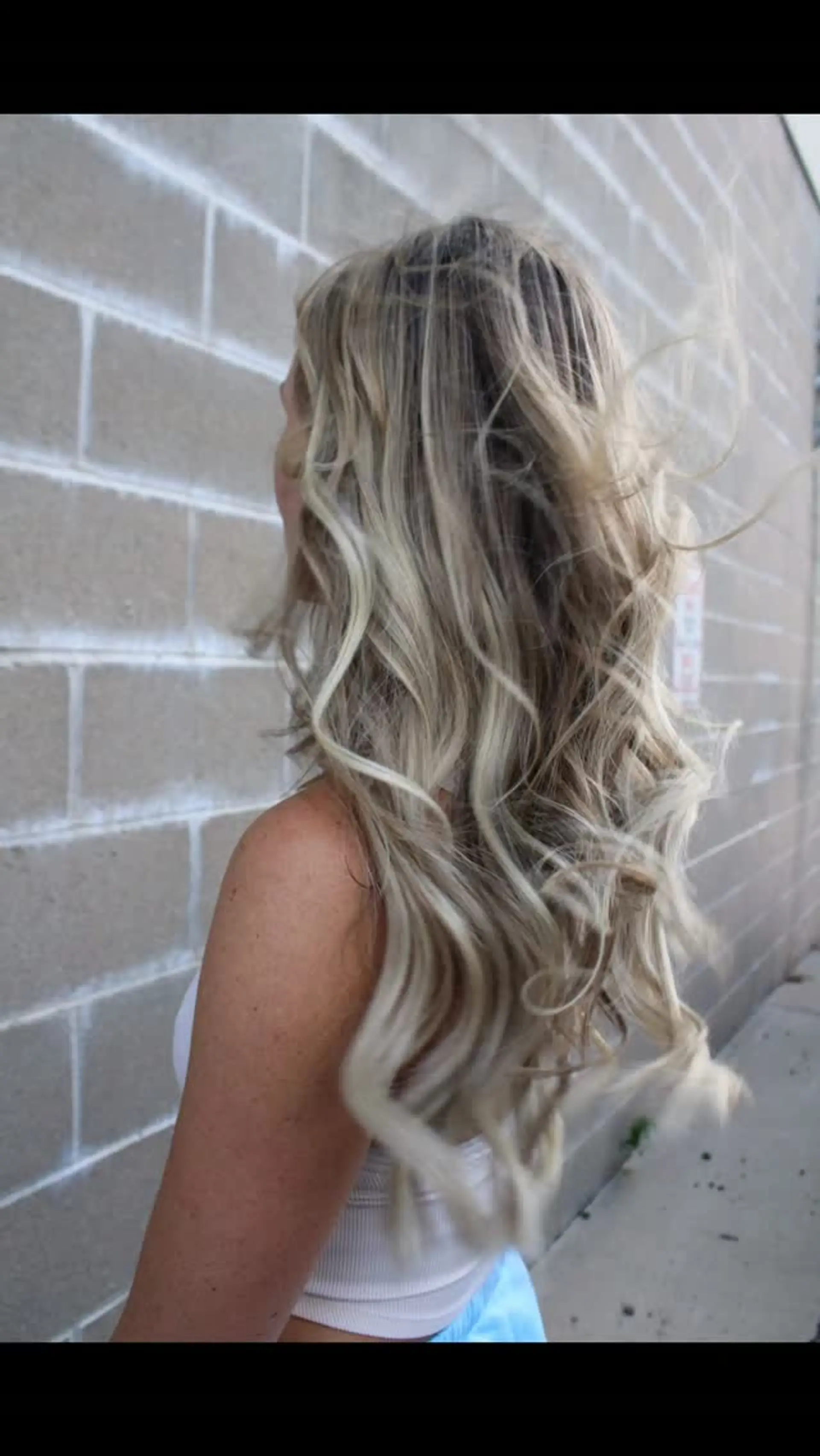 Long, flowing dimensional blonde hair styled in soft, loose waves with seamless extensions. 1