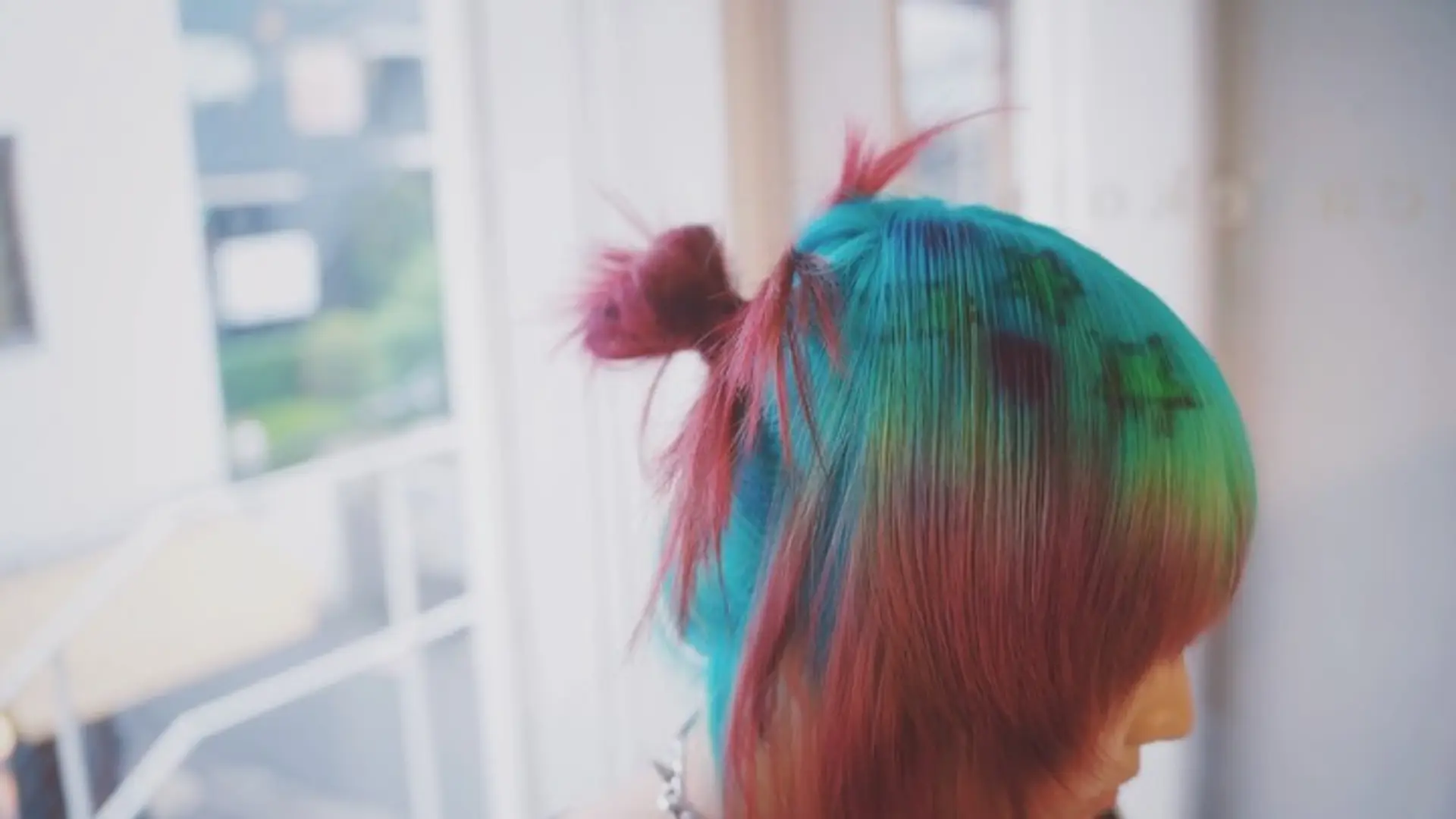A bold, colorful style featuring vivid teal and bright pink layered tones adorned with stenciled star designs and styled into a playful half-up mini bun. 1