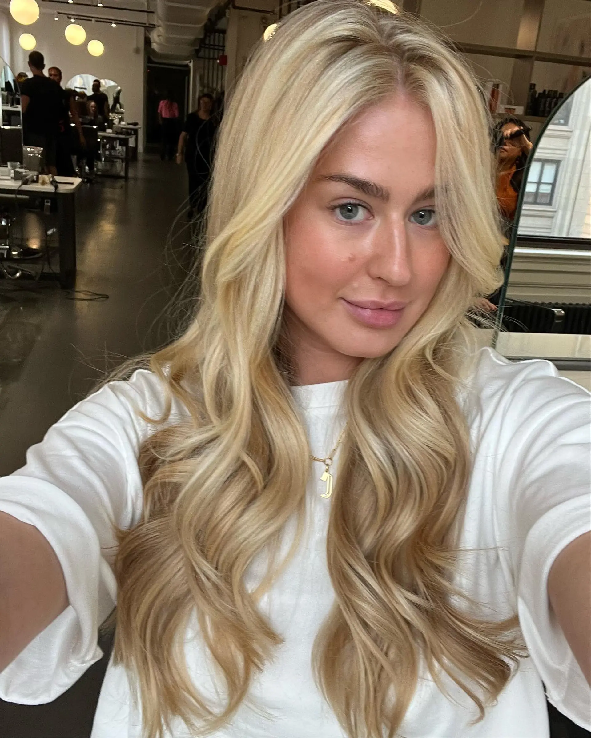 Long, luminous blonde balayage styled in soft, cascading waves with bright face-framing ribbons. 1