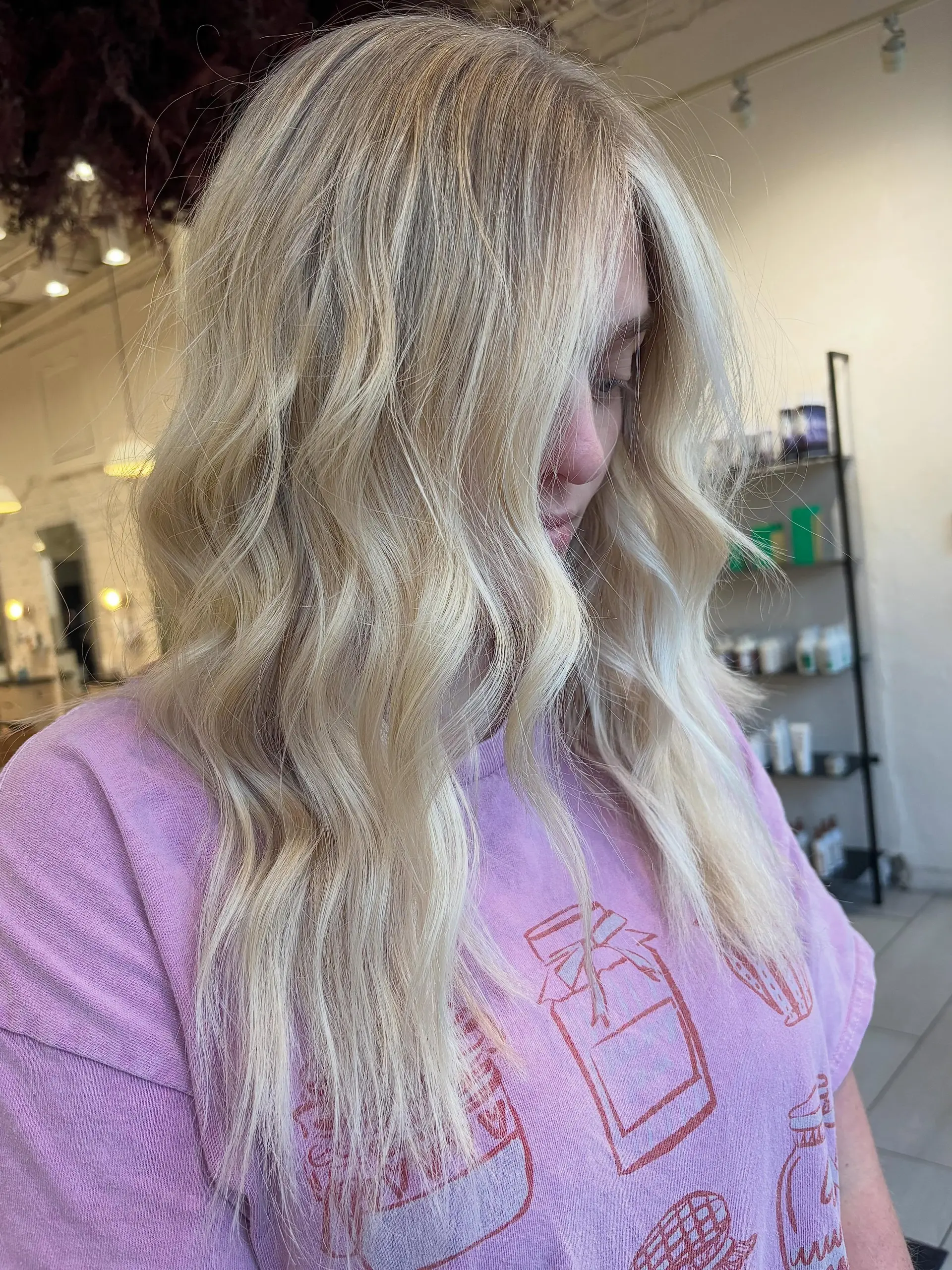 Long bright platinum blonde hair styled with loose, effortless textured waves and curtain layers framing the face. 1