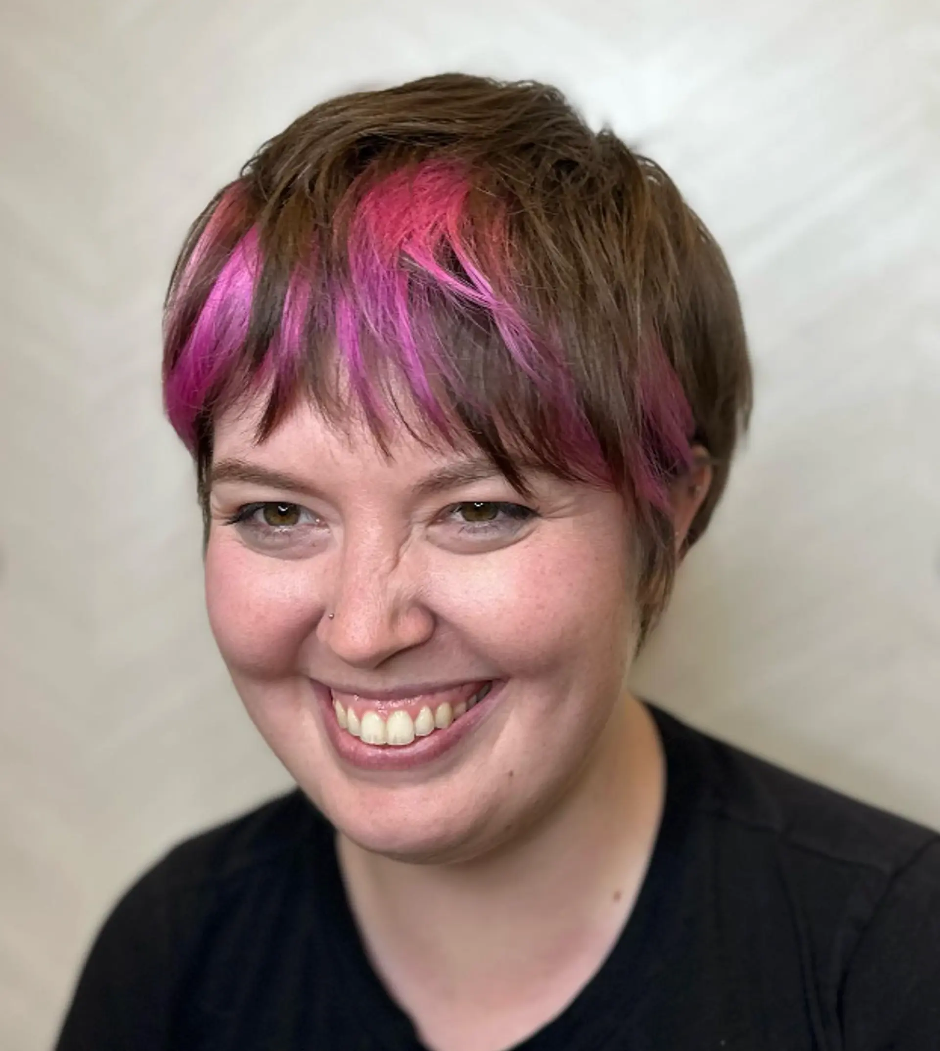 A short pixie-style cut with a vibrant pink burst along the brown fringe, creating a bold bicolor contrast and edgy appearance.

Color by @simabeautynyc
Cut and style by @juliamannino_hair
 1