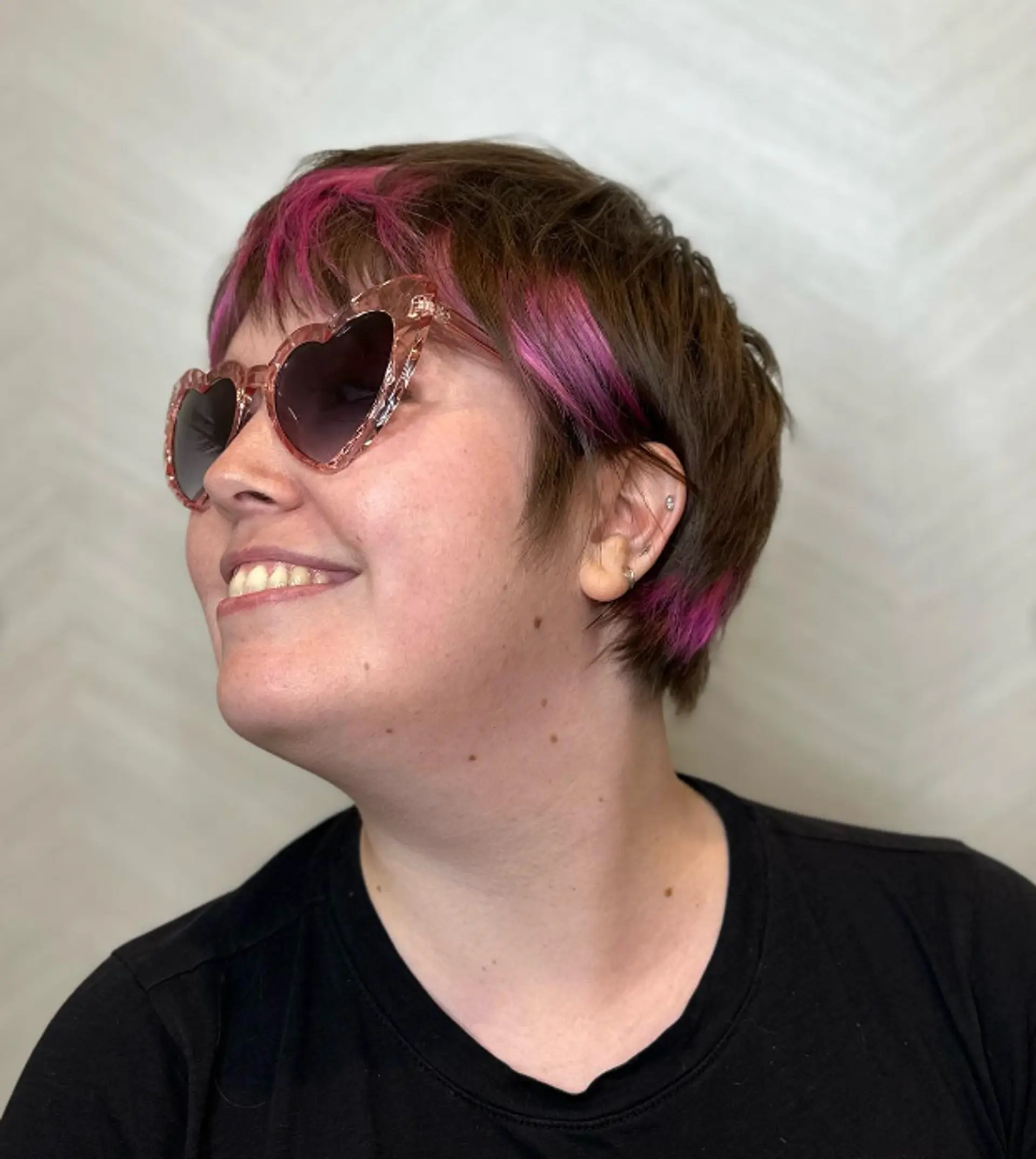 A short pixie-style cut with a vibrant pink burst along the brown fringe, creating a bold bicolor contrast and edgy appearance.

Color by @simabeautynyc
Cut and style by @juliamannino_hair
 2