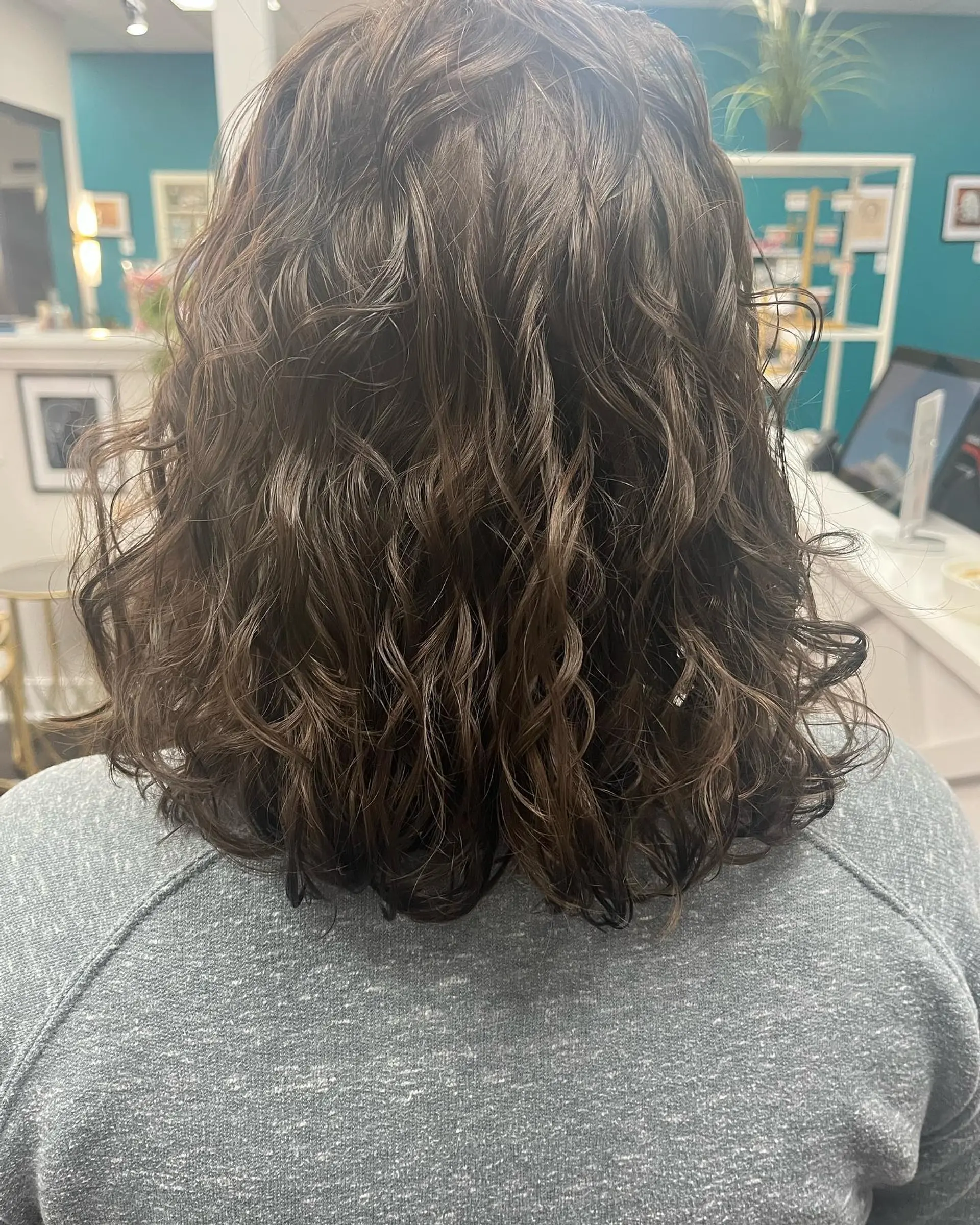 Shoulder-length brunette long bob styled with defined natural curls and subtle layering. 1