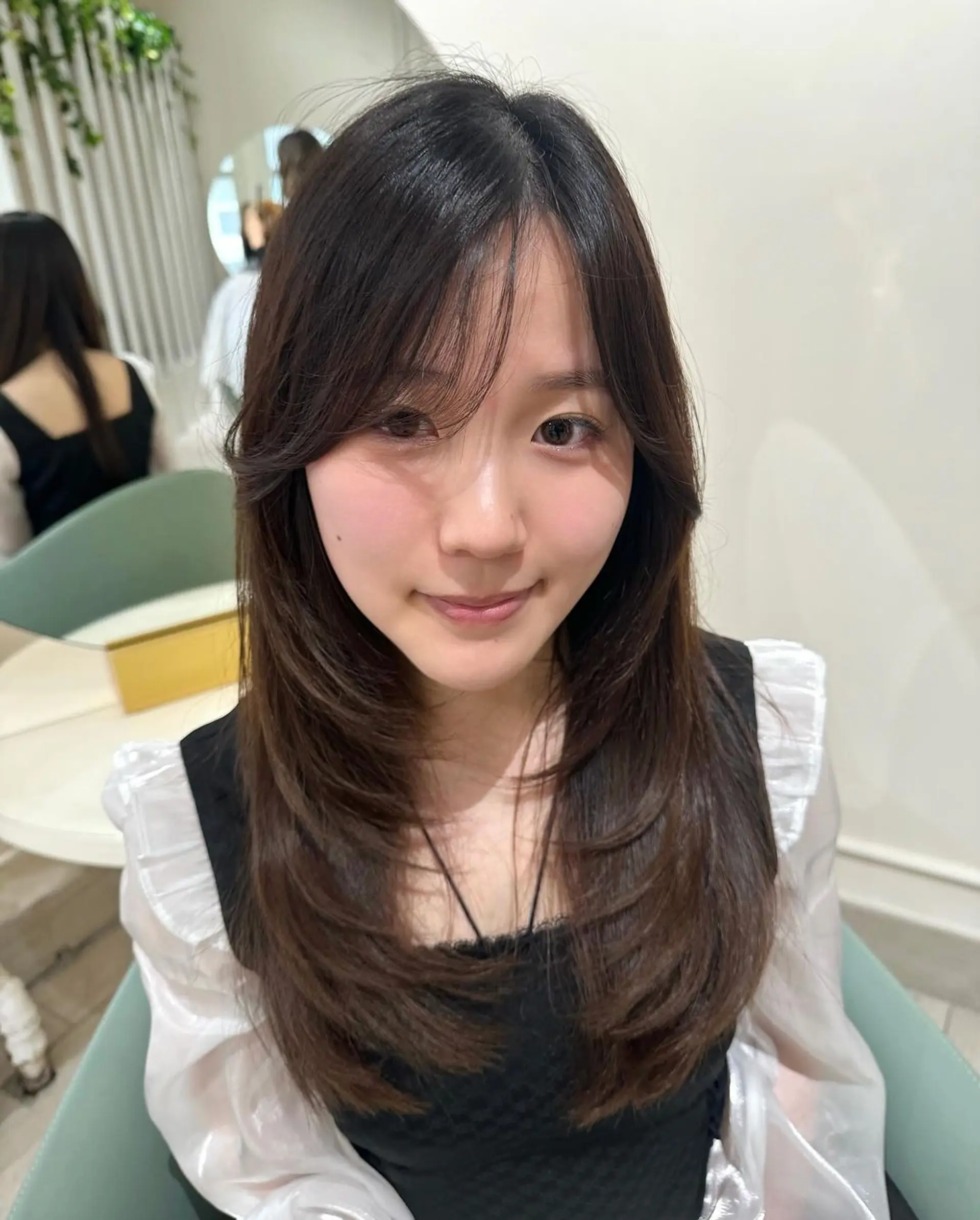 Long, dark brown, straight hair with face-framing layers and subtle side bangs. The natural shine and gentle flow of the hair create a chic and elegant look. 2