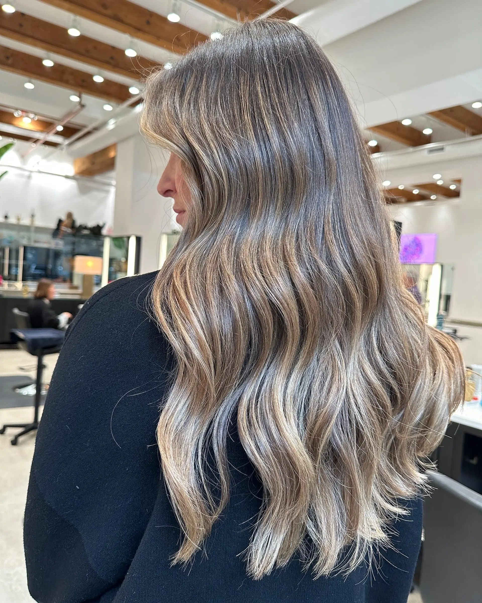 A long, wavy hairstyle featuring a seamless balayage transition from brown roots to caramel and blonde ends. 1