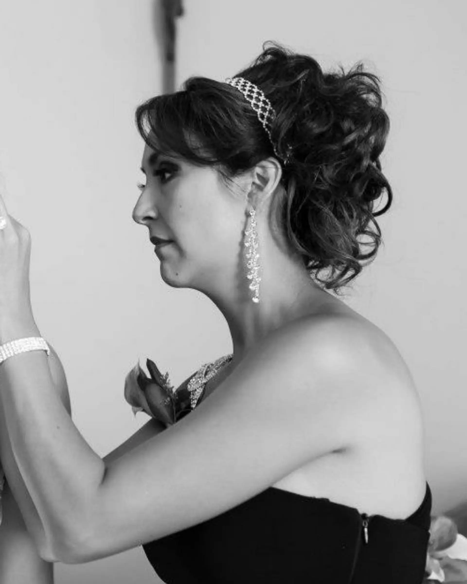 A glamorous formal updo featuring pinned curls, side-swept fringe, and a sparkling crystal headband. 1