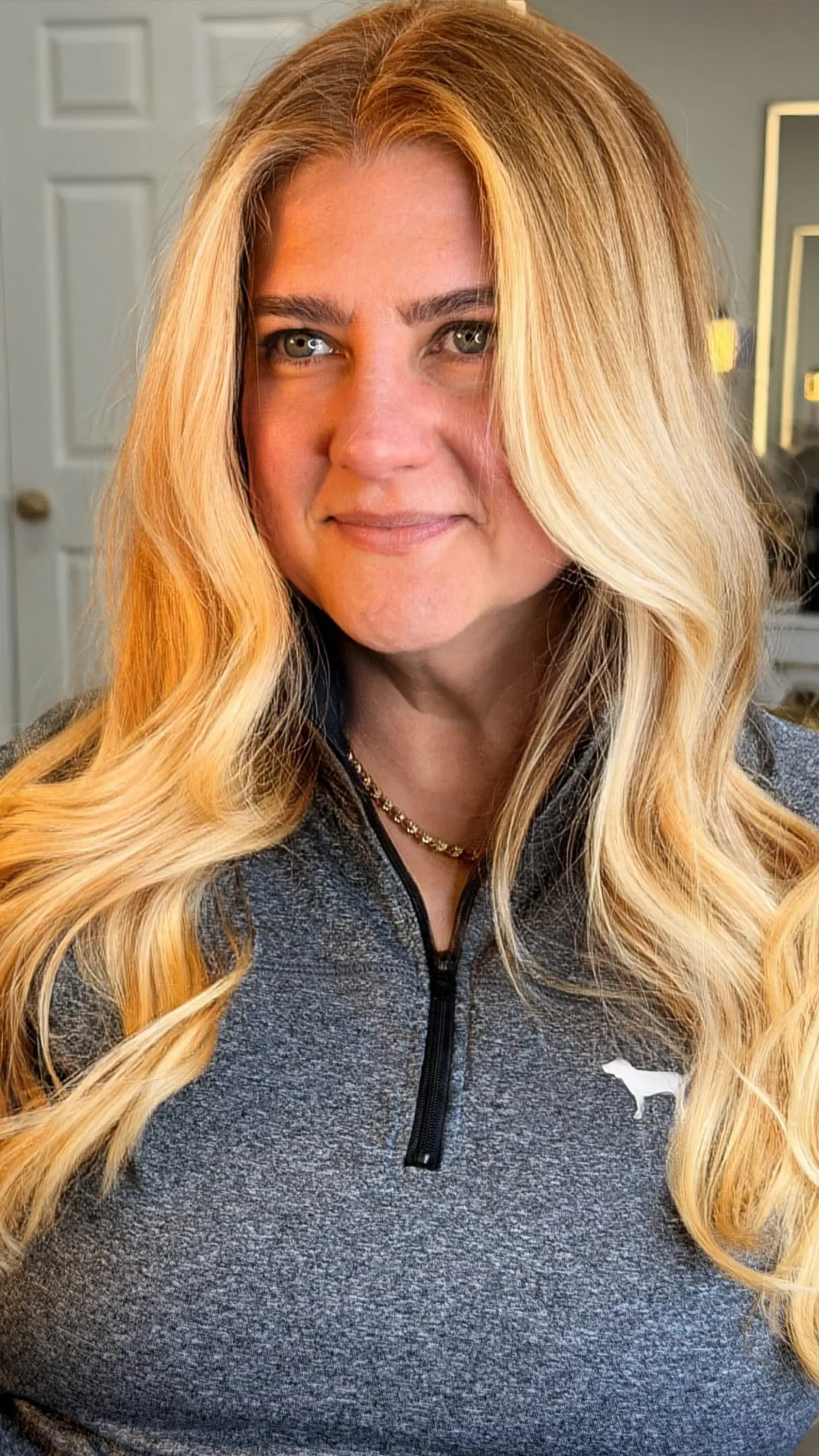 Long dimensional warm blonde hair styled in voluminous, soft cascading waves with bright face-framing pieces. 1