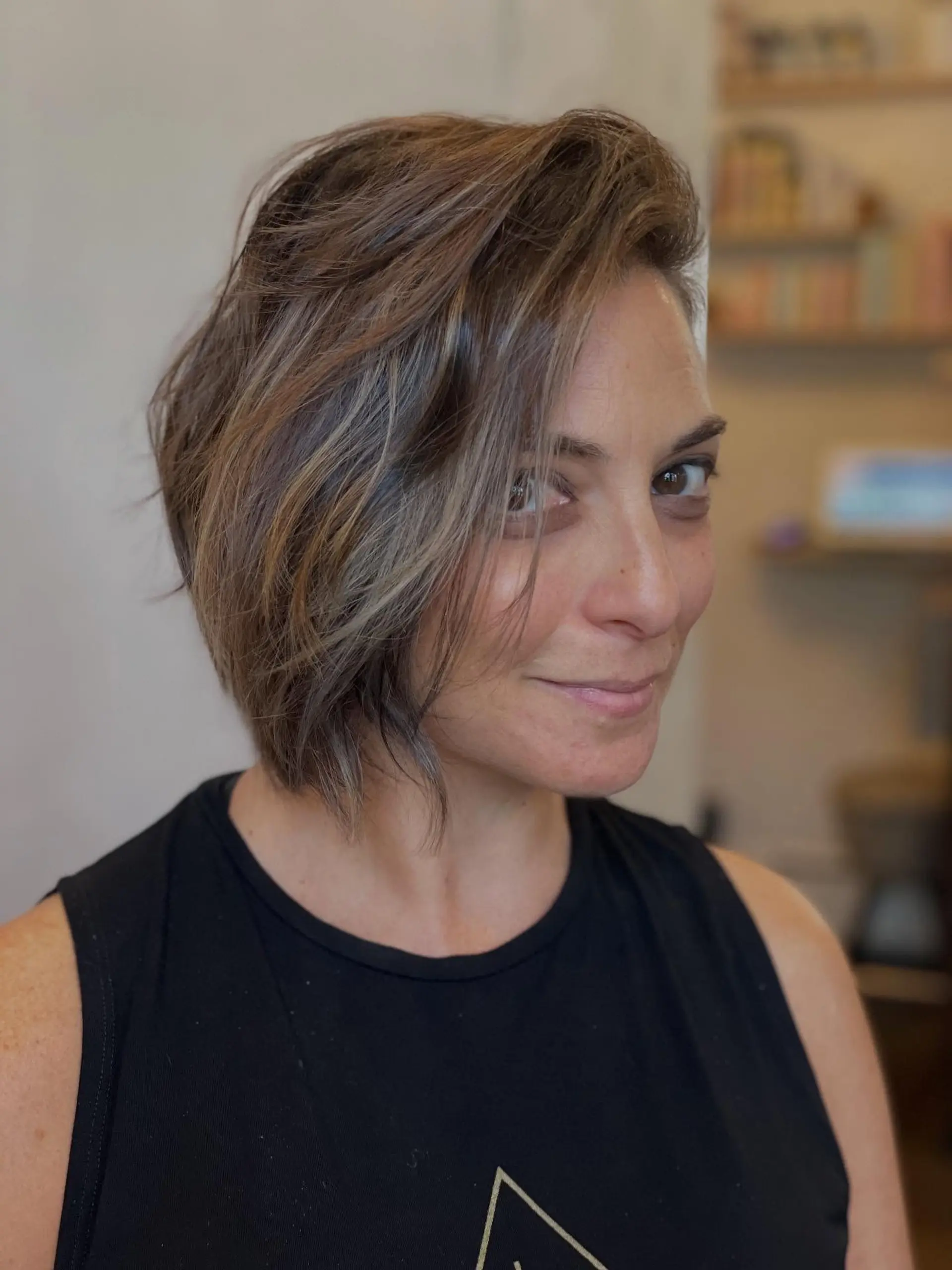 A layered, asymmetrical short bob with side-swept bangs and multi-toned dimensional highlights. Current Cut My Hair service: $215 for haircut and included finish only; displayed color is not included. 1