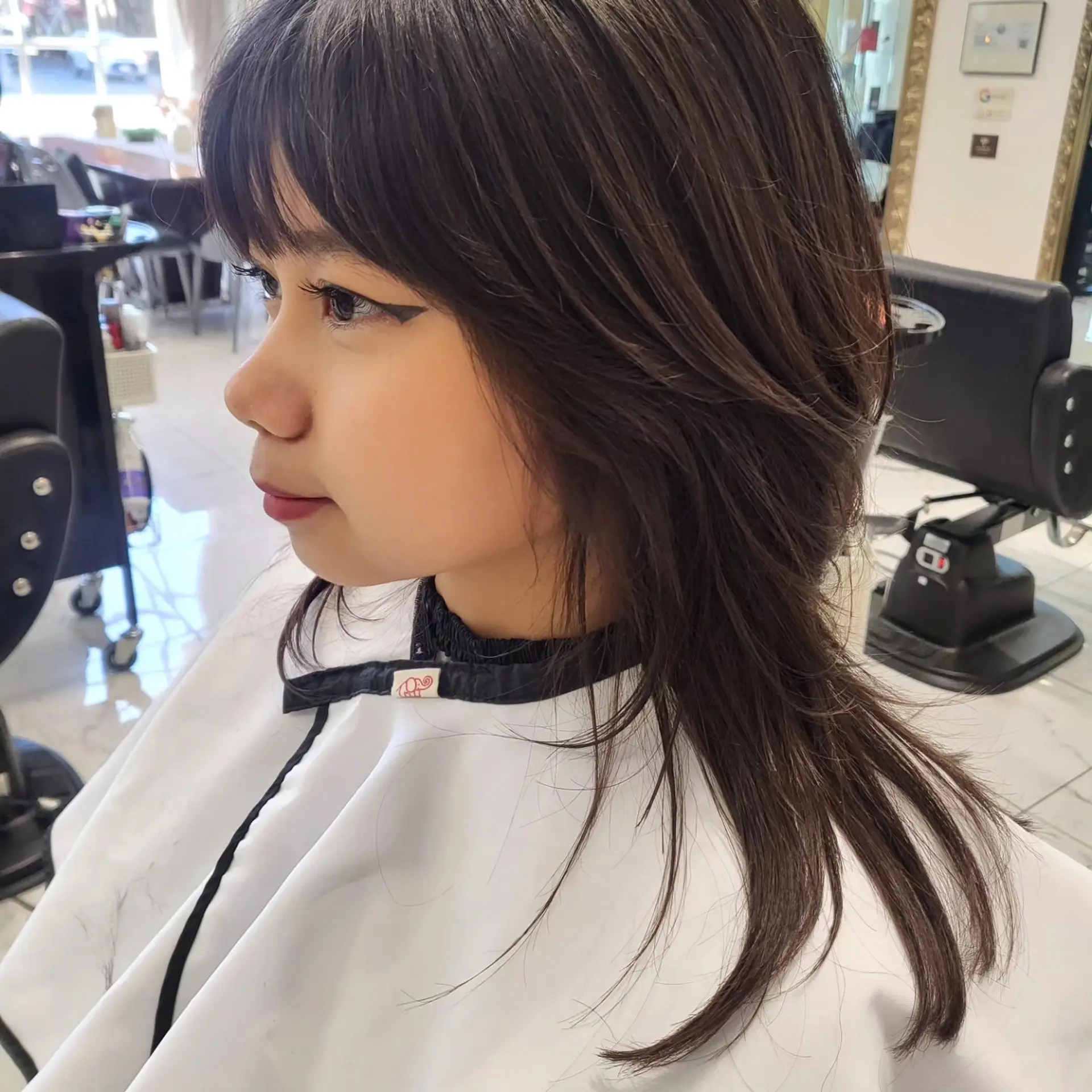 A medium-length layered shag haircut featuring face-framing feathered layers and full front bangs. 1