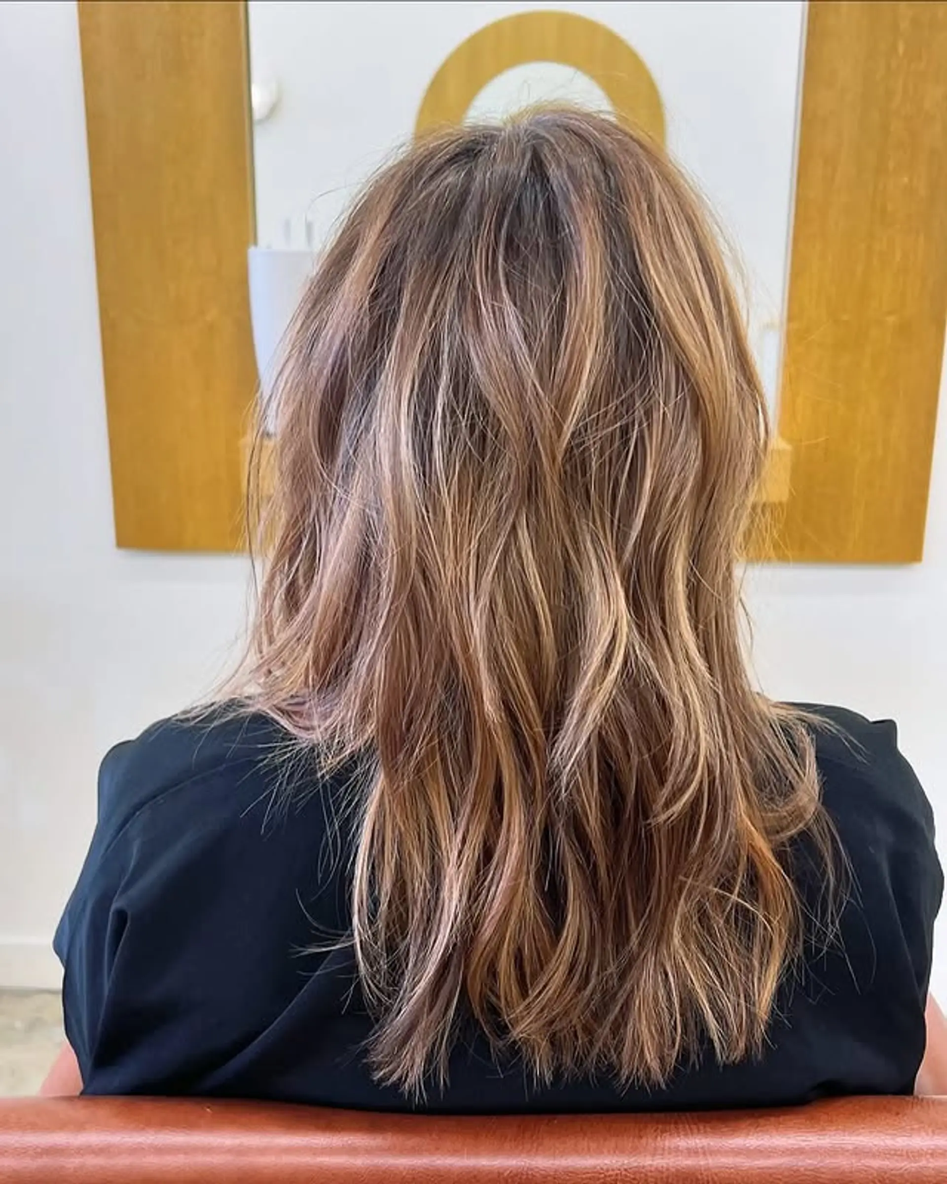 A layered, wavy hairstyle with a bronde color and natural-looking highlights. 1