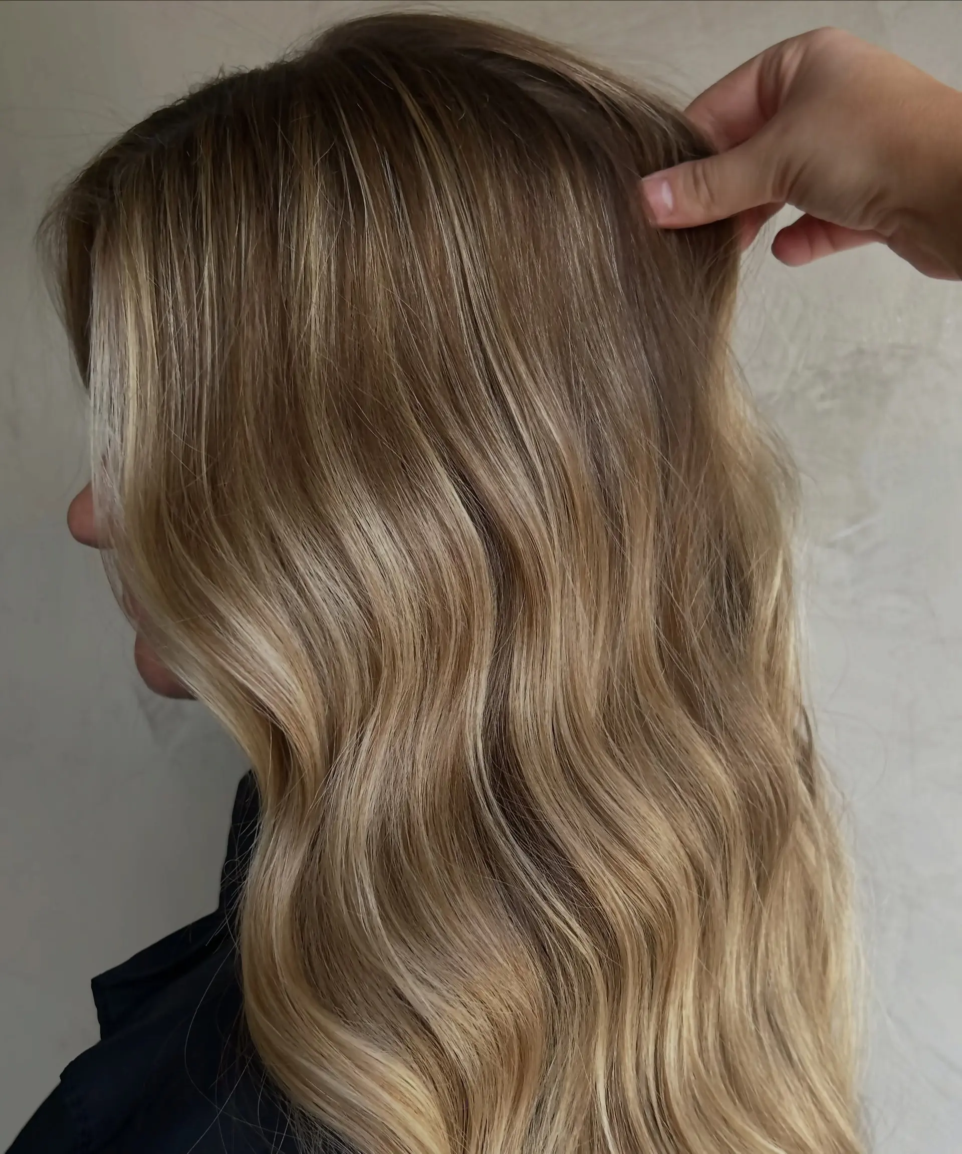 Long cascading hair styled in loose, soft waves featuring finely blended multidimensional blonde highlights over a light brown base. 1