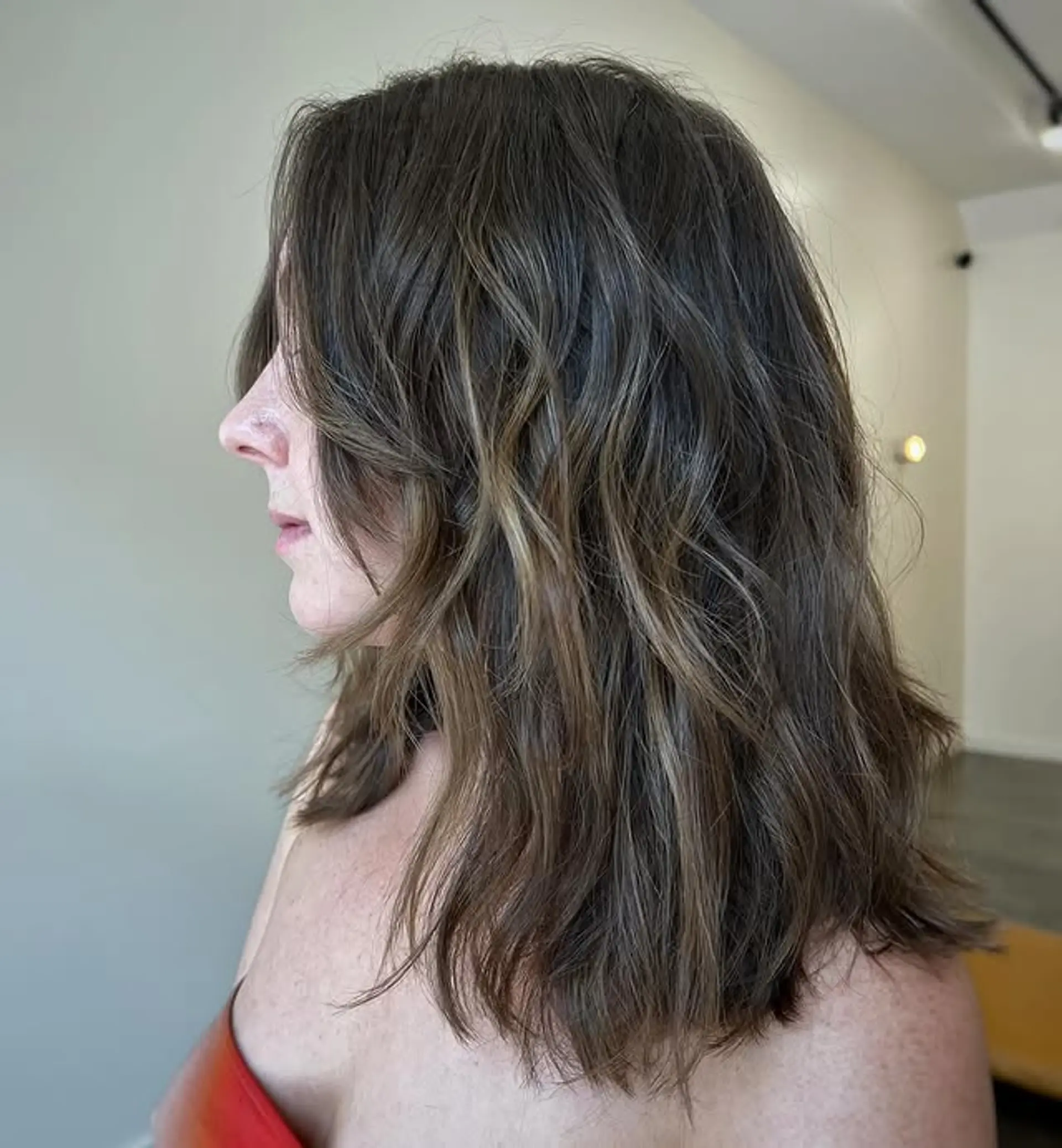 A medium-length wavy hairstyle with face-framing layers and beach waves. 1