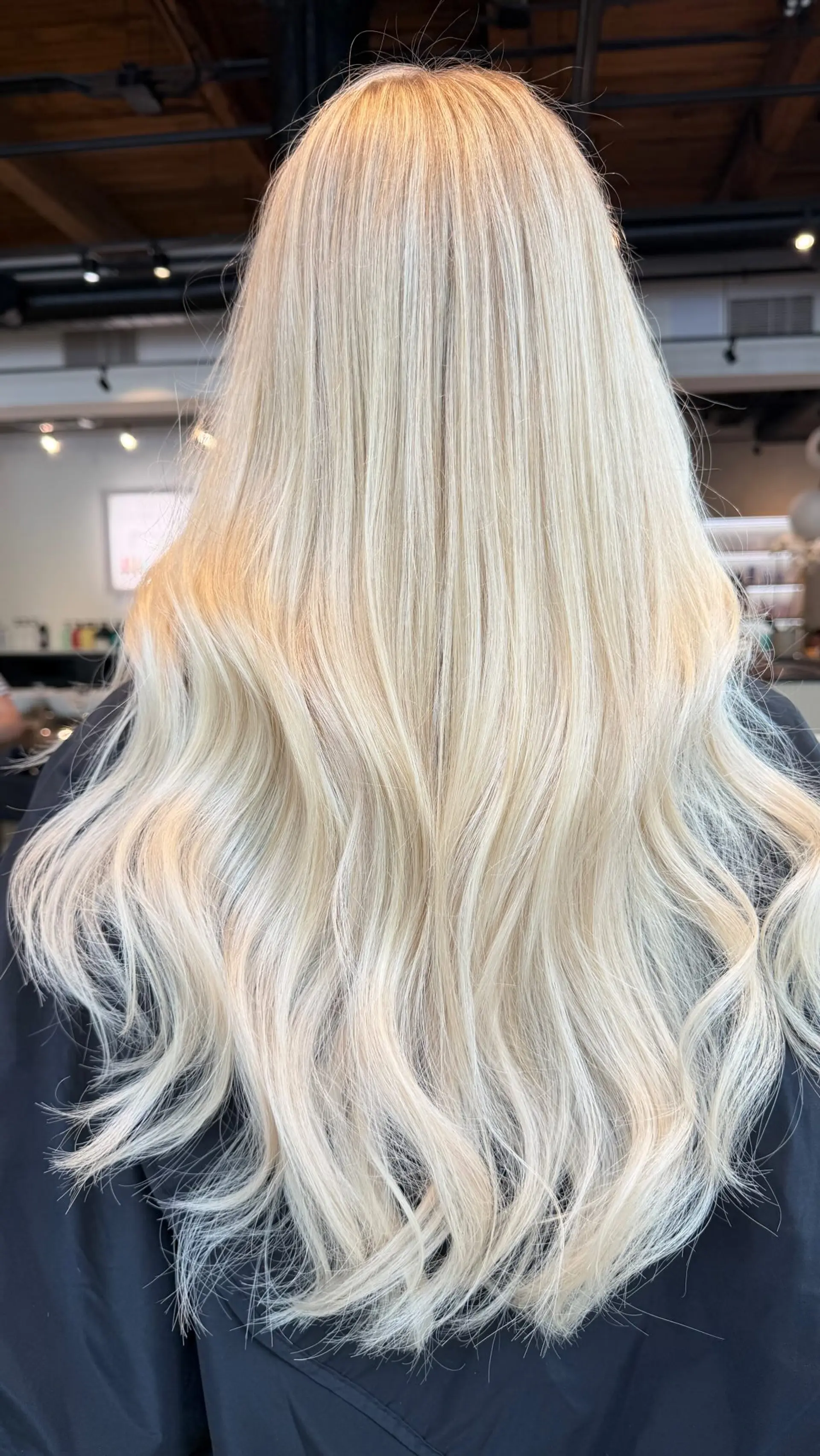 Long blonde hair styled with a smooth top section and loose, effortless waves through the mid-lengths and ends. 1